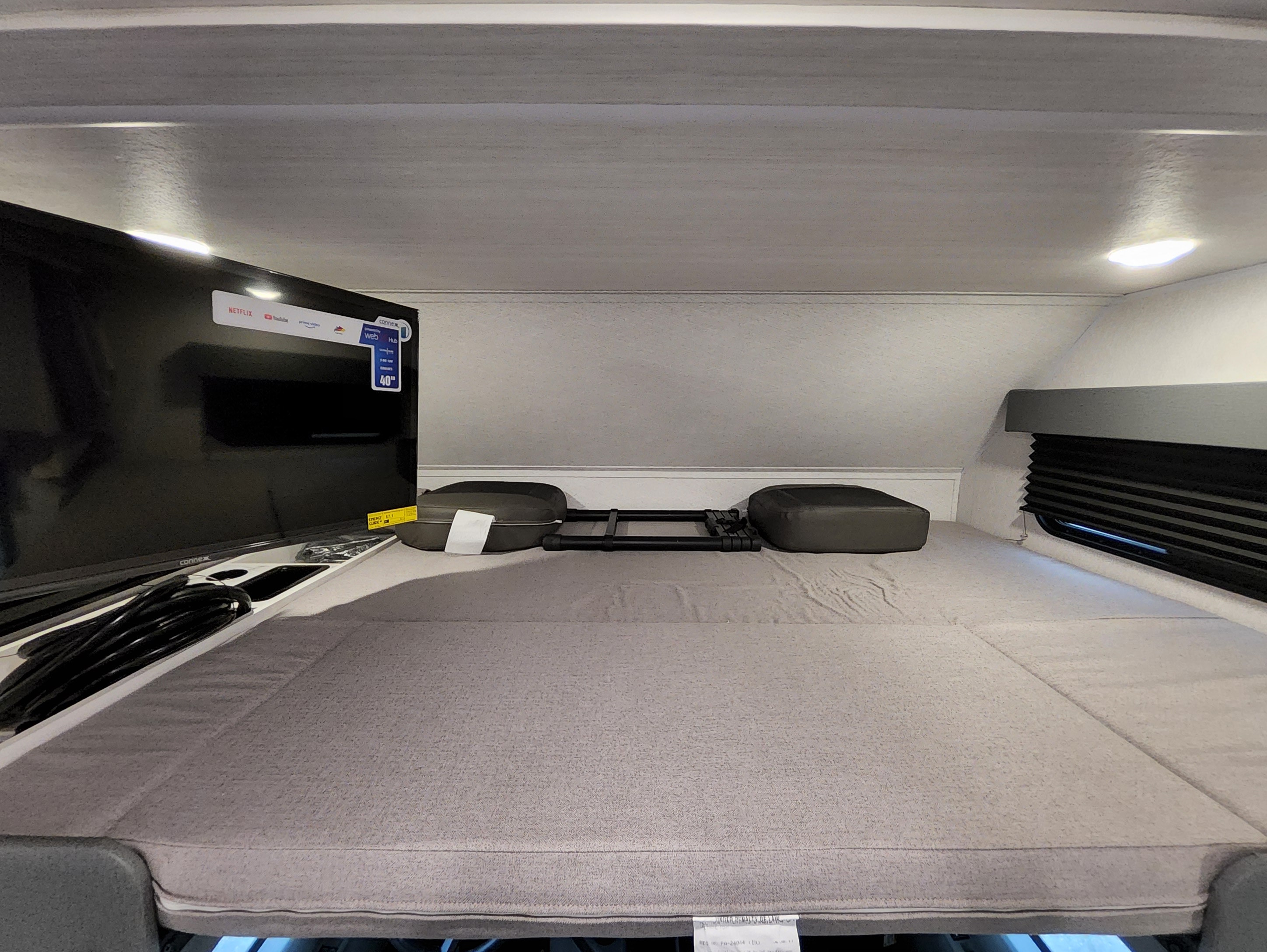 This RV rental's cozy sleeping area features a large 40" smart TV, window, and comfy mattress.. East To West Entrada 2025