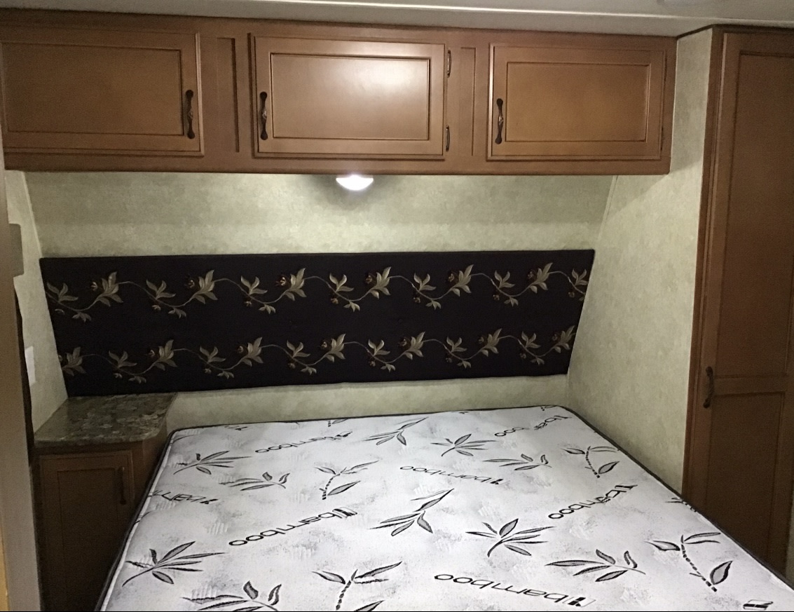 RV rental: Cozy bedroom featuring a patterned headboard, comfy bamboo mattress, overhead cabinets, and built-in storage.. Gulf Stream Kingsport 2015