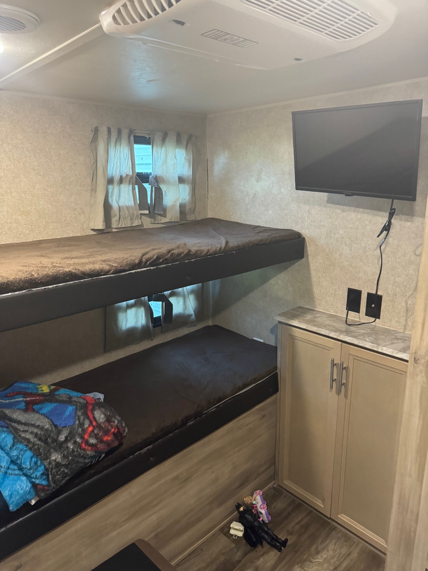 Cozy RV rental bunkhouse interior features two beds, a wall-mounted TV, and cabinets, ideal for compact travel.. Forest River Coachmen Catalina Legacy 2020
