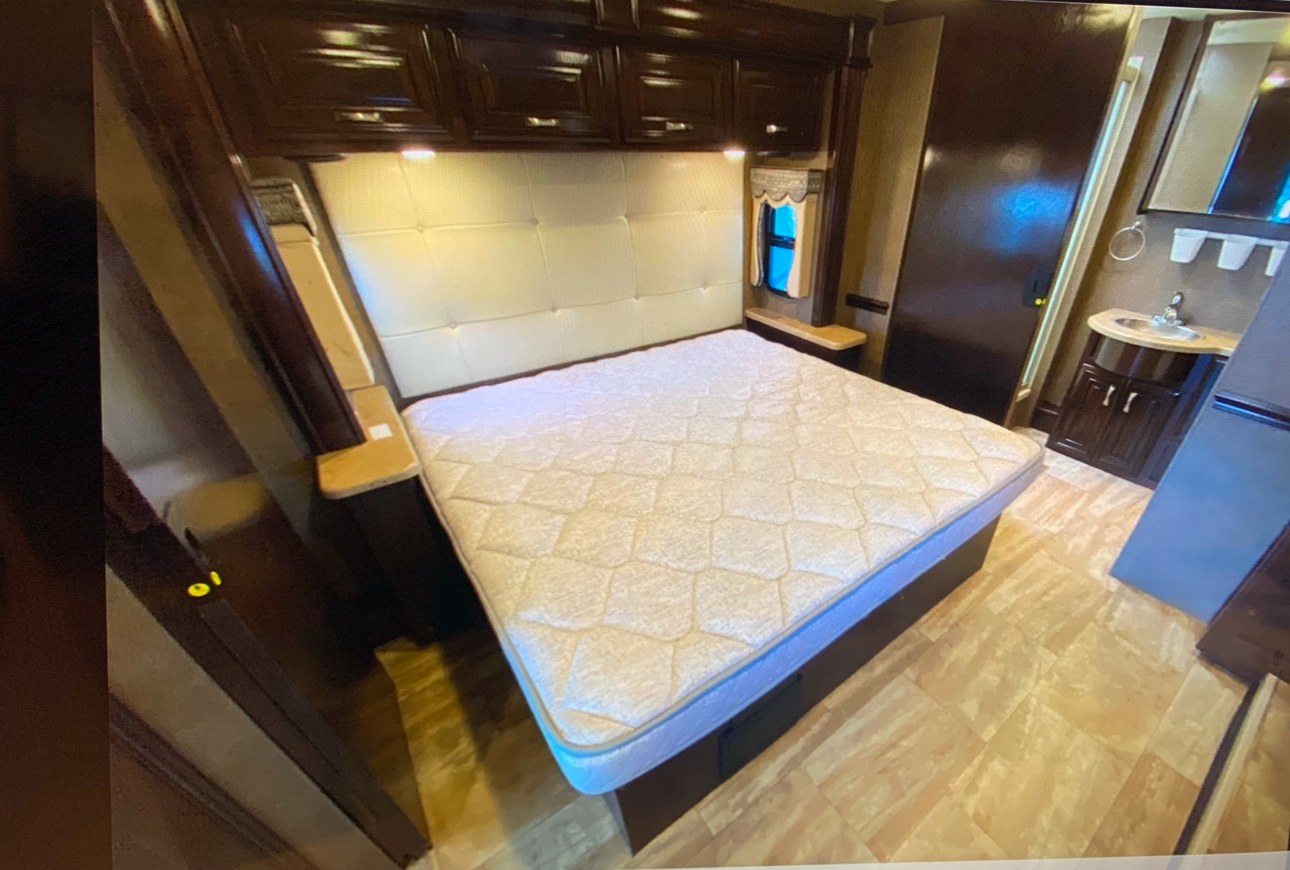 Spacious RV rental bedroom with a comfy queen bed, padded headboard, and attached bathroom vanity. Perfect for travel.. Thor Challenger 2017