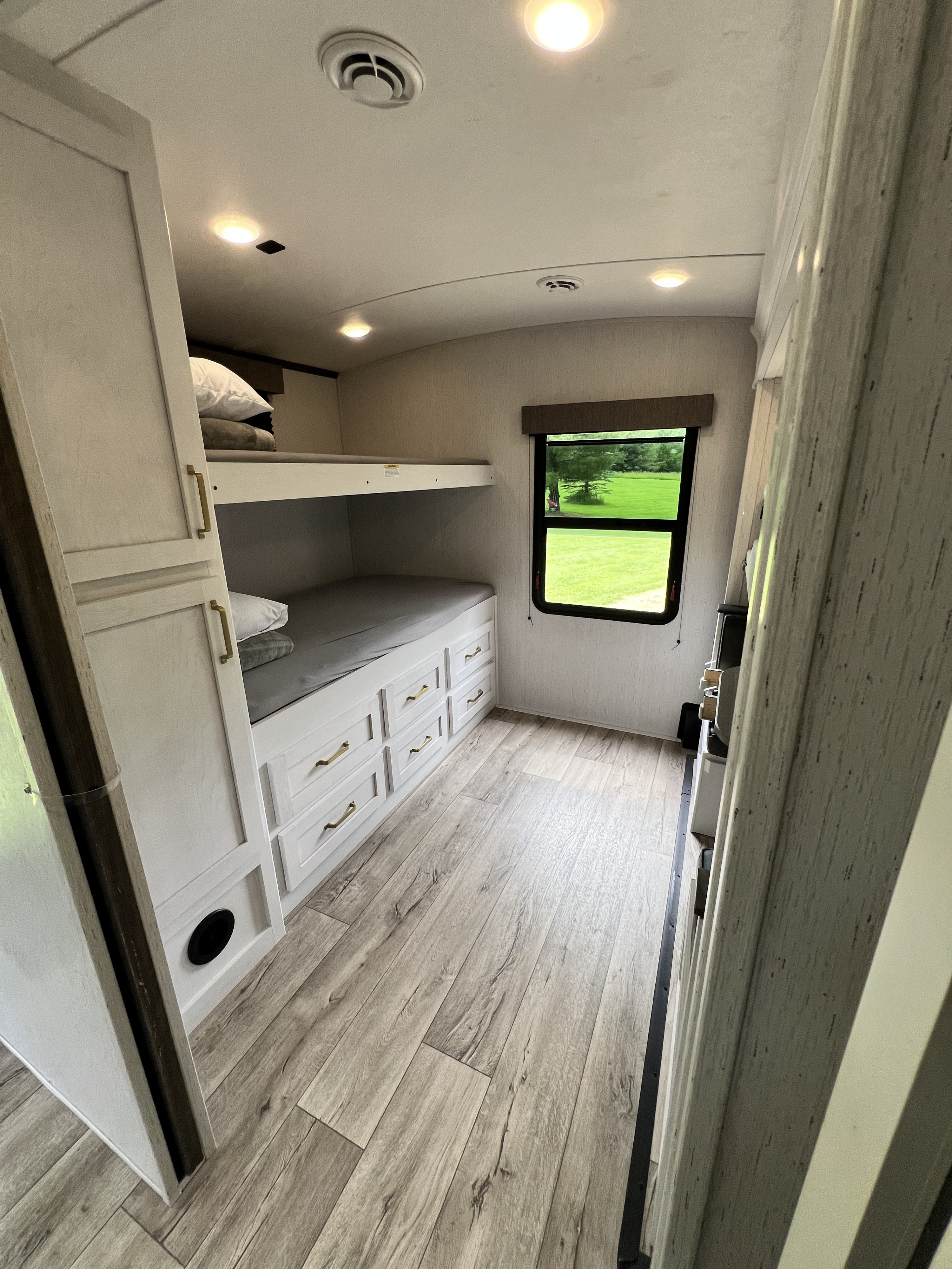 Spacious RV rental bunkhouse with modern bunk beds, built-in storage drawers, and a large window offering outdoor views.. Dutchmen Astoria 3203BH 2022