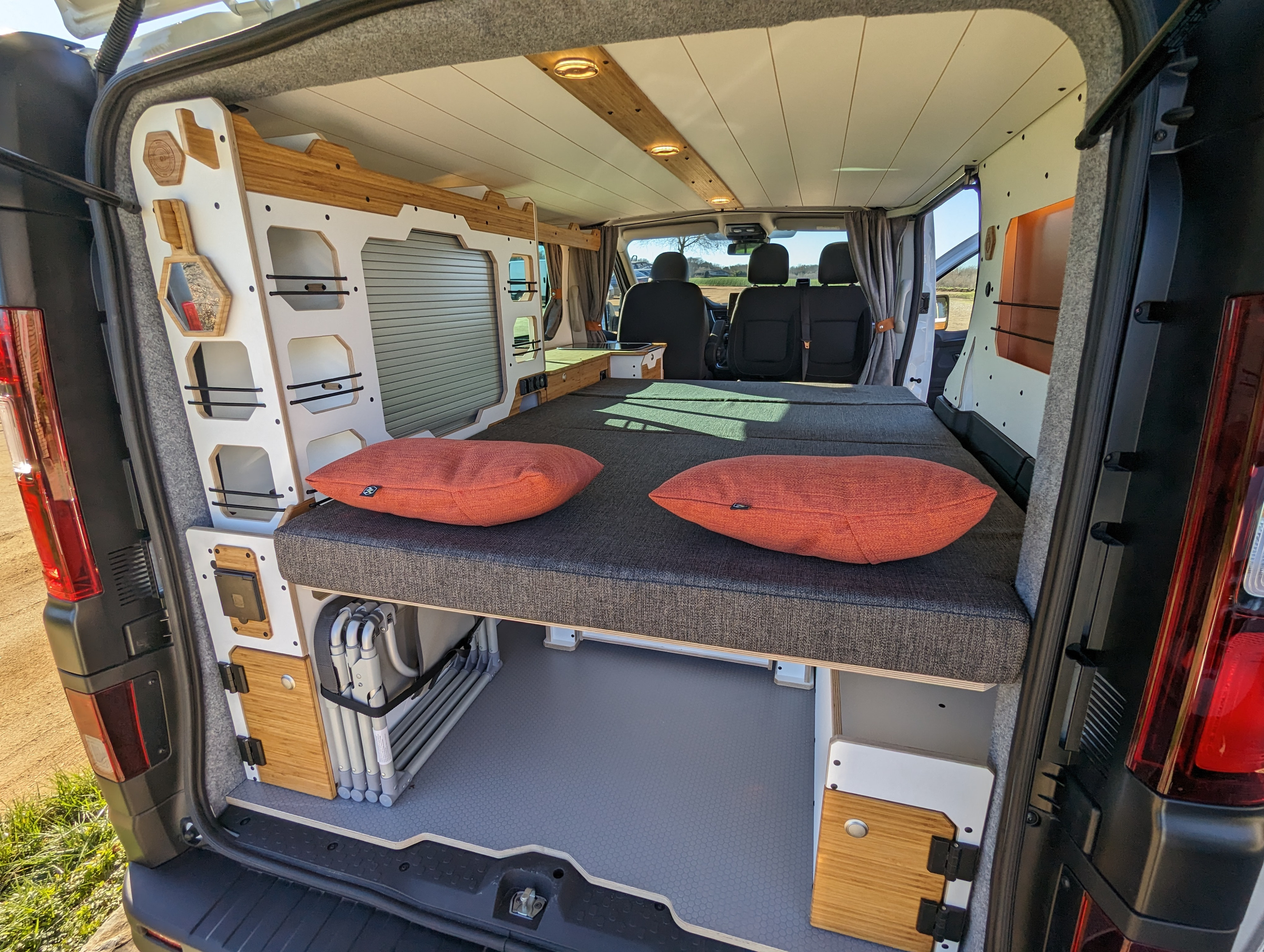 Spacious RV rental interior with a comfy bed, modular storage, and a bright front cabin view. Ideal for adventures.. Renault Trafic 2025