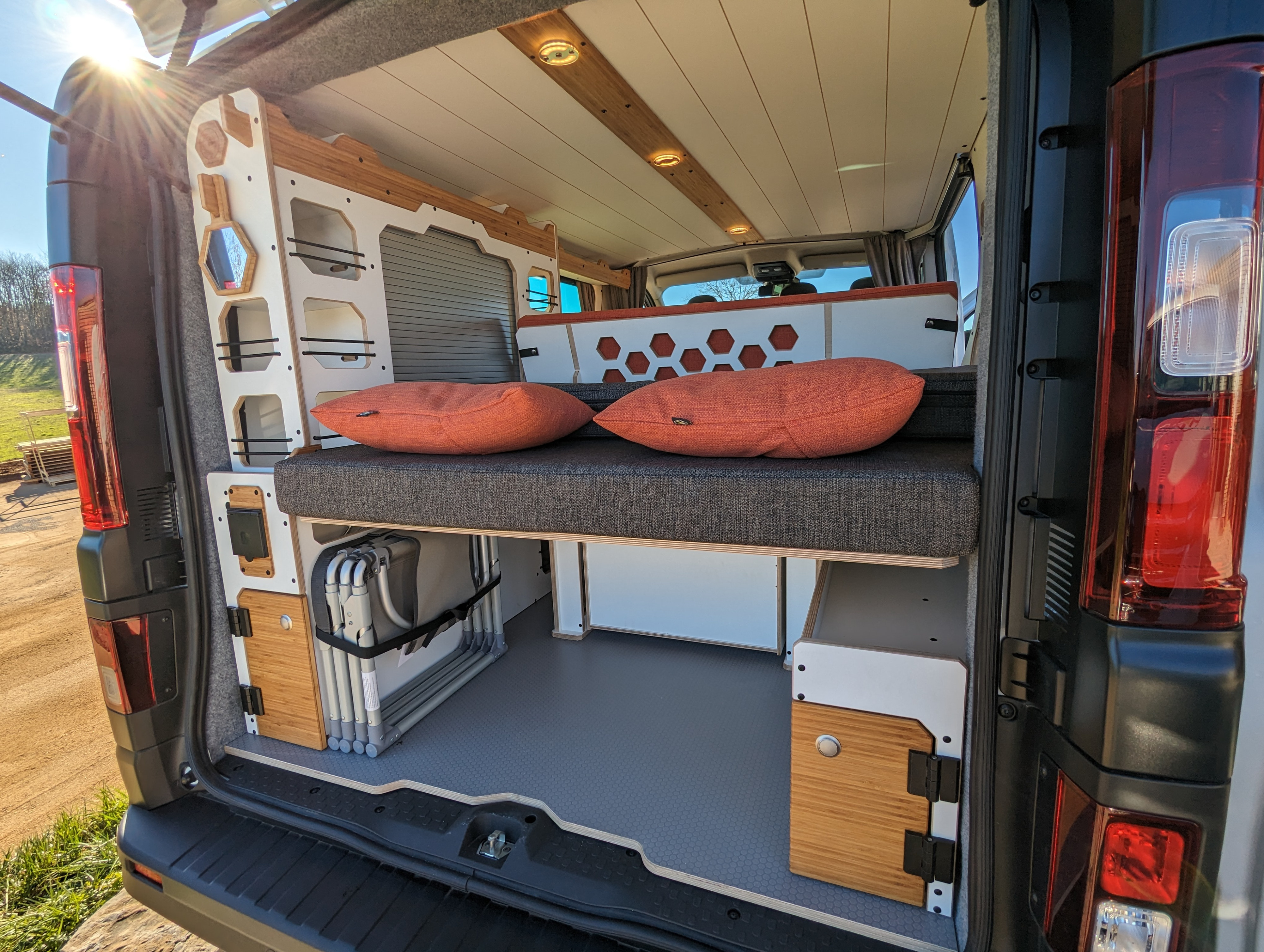 Spacious custom camper van interior perfect for an rv rental, featuring comfy bed, clever storage, and stylish design.. Renault Trafic 2025