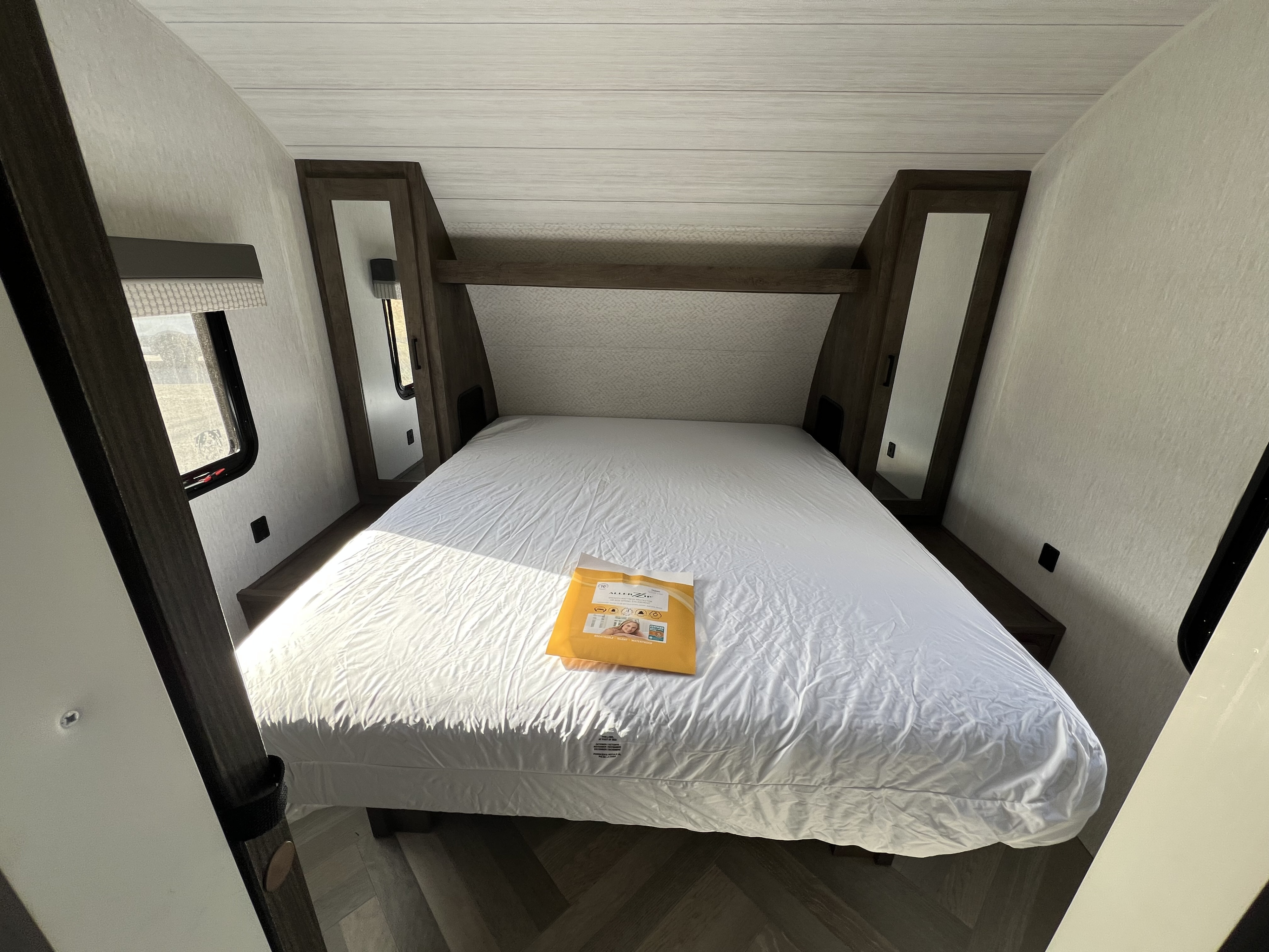 RV rental bedroom: Clean interior with a white bed, wooden headboard, mirrored cabinets, and a new mattress protector.. Forest River Salem Cruise Lite 2022