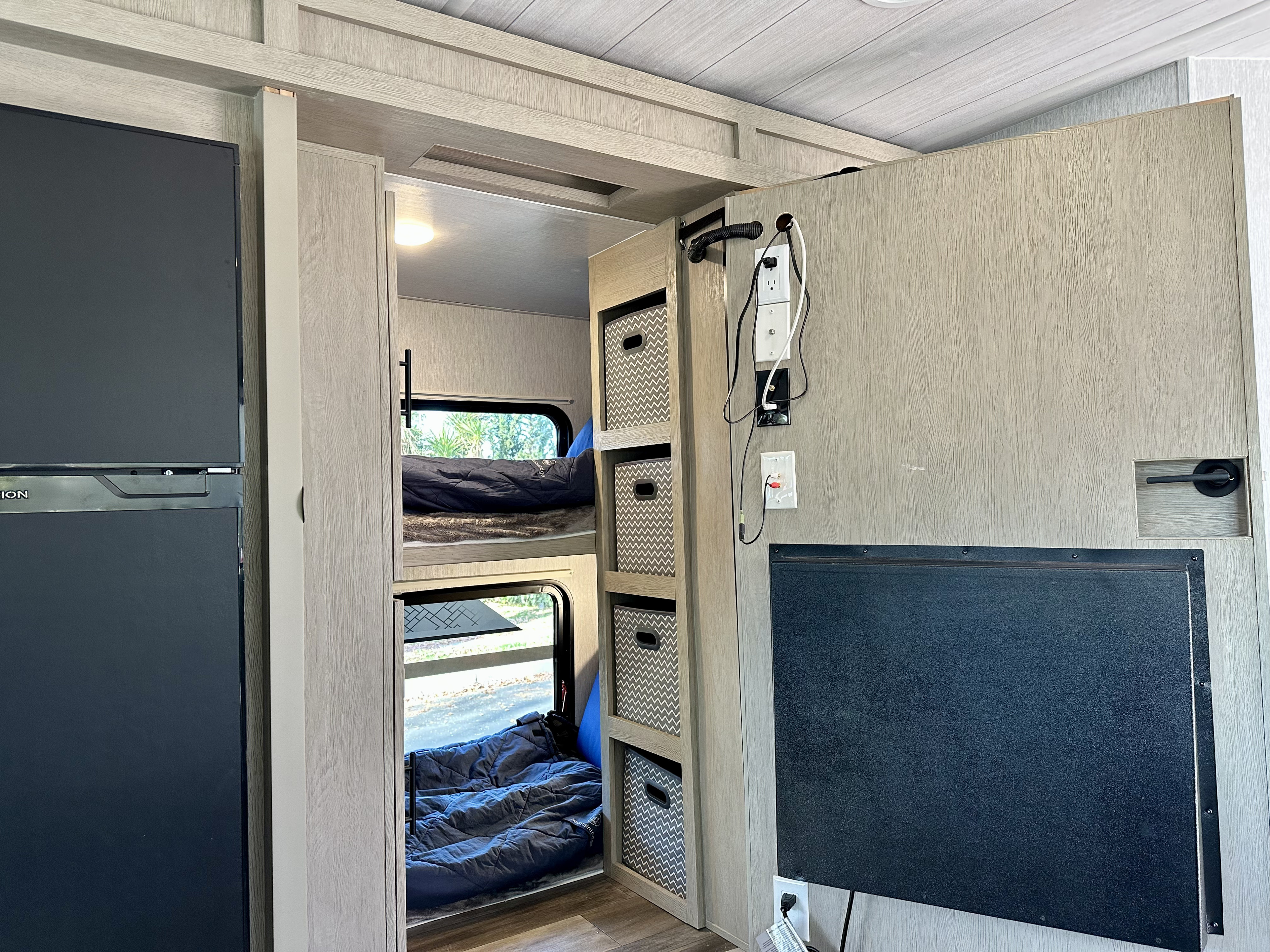 RV rental interior showcasing space-saving bunk beds, storage cubbies, a refrigerator, and entertainment area for road trips.. Forest River T2510HBL 2024