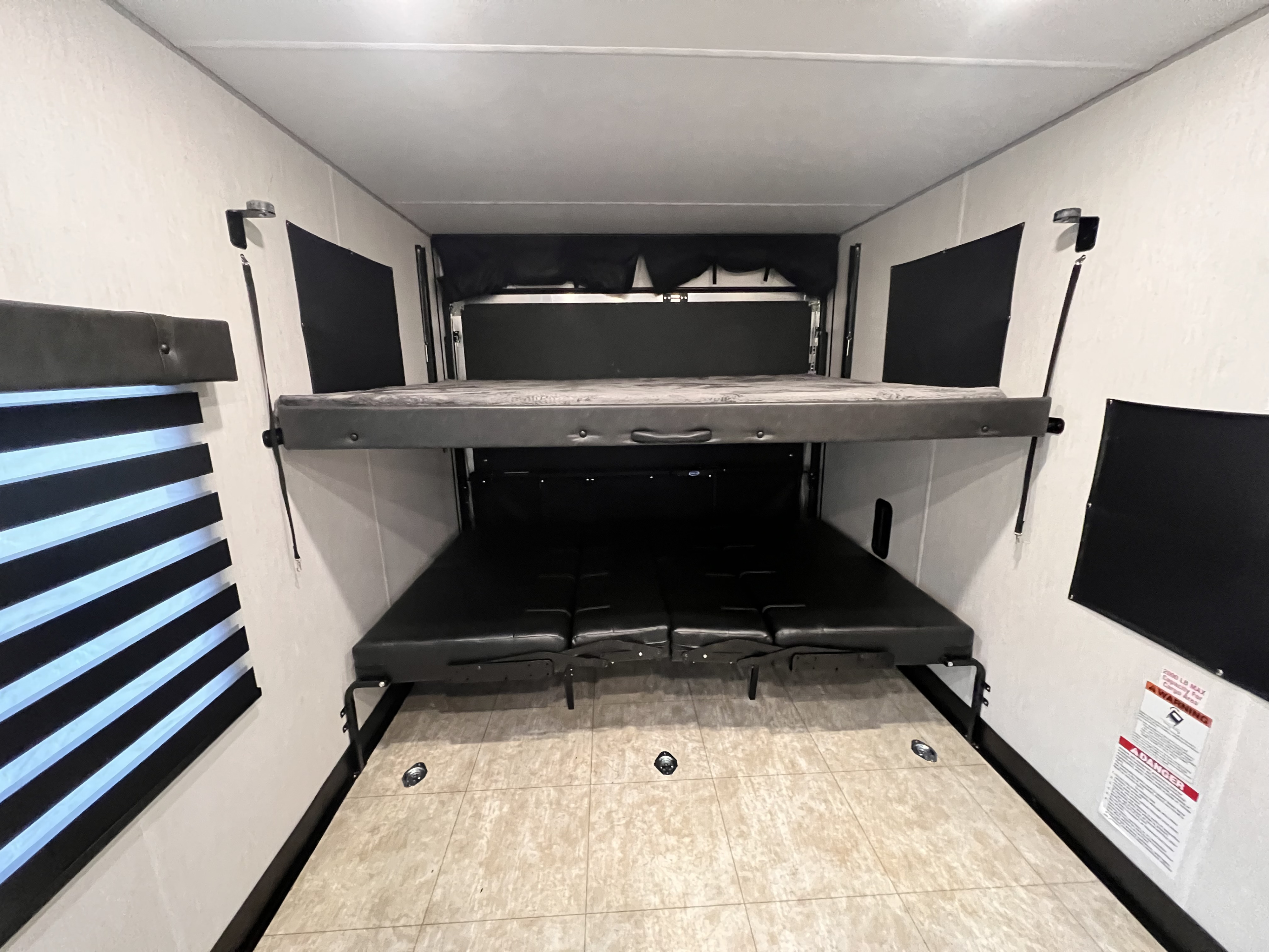 RV rental toy hauler interior showing convertible bunk beds and cargo tie-downs. A versatile space for sleep and gear.. Forest River 29ks rouge 2022