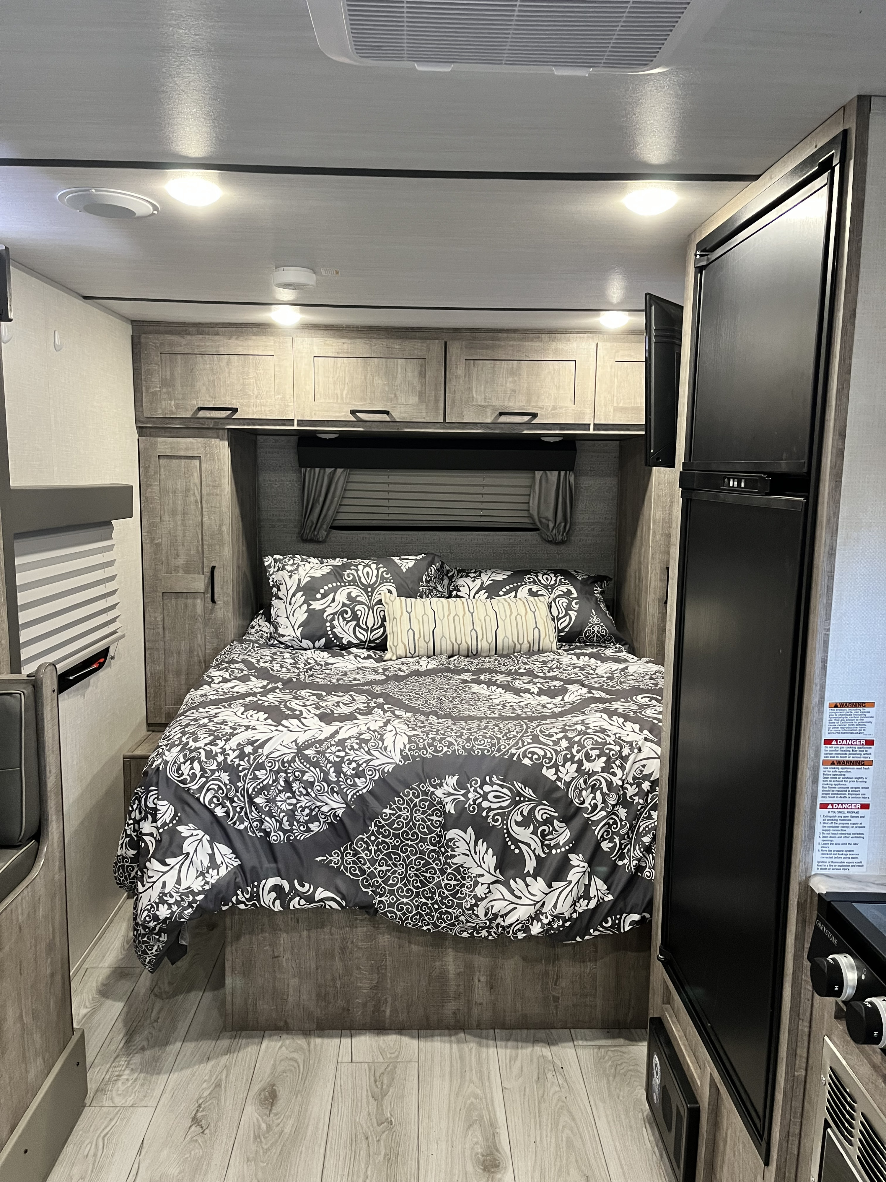 RV rental bedroom: Enjoy comfortable sleep on a patterned bed with ample overhead storage and convenient amenities.. Forest River Surveyor Legend 2023
