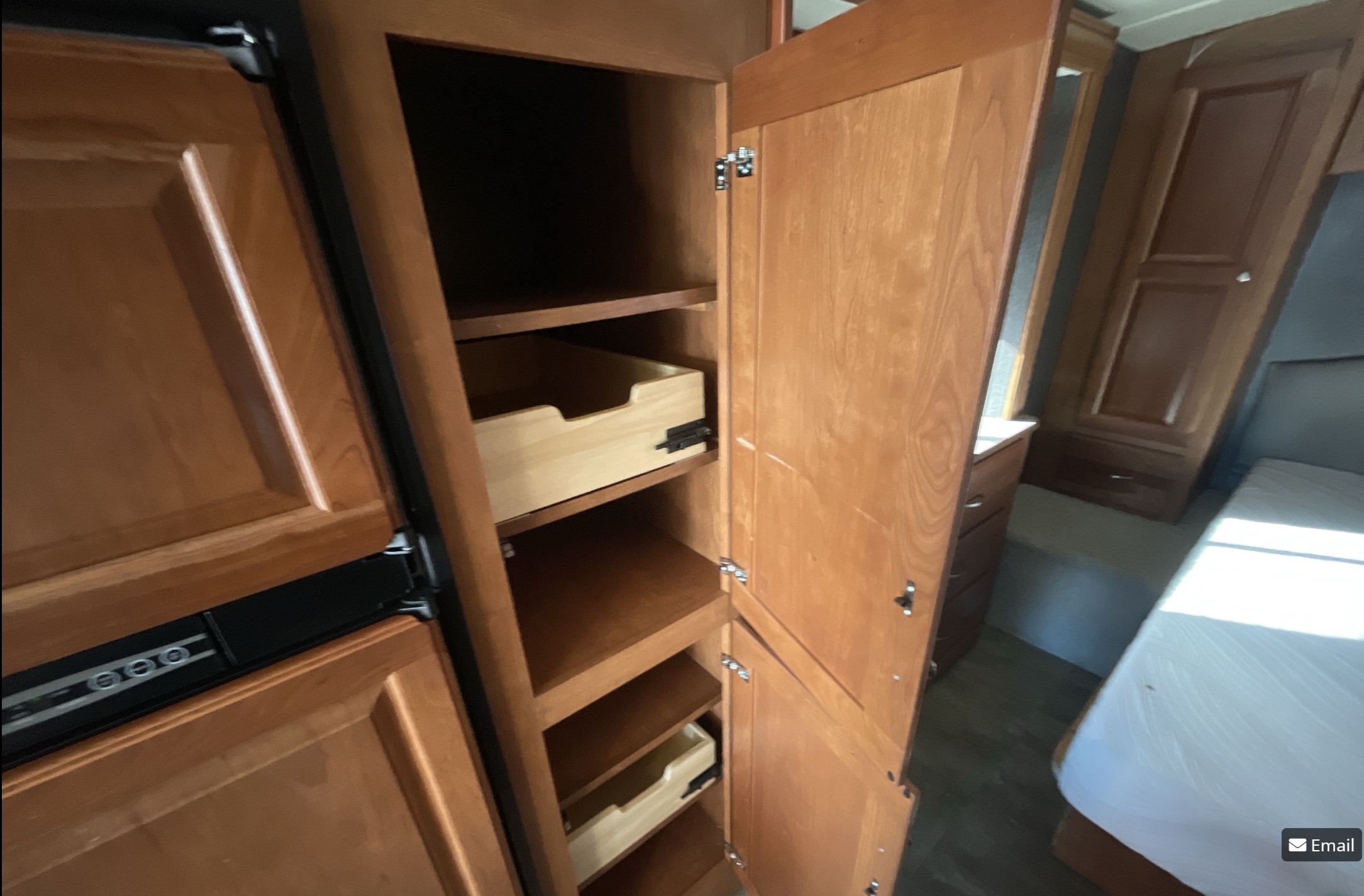 RV rental pantry: Open wooden cabinet with shelves and pull-out drawers, perfect for organizing. Bedroom visible beyond.. Winnebago Vista LX 2017