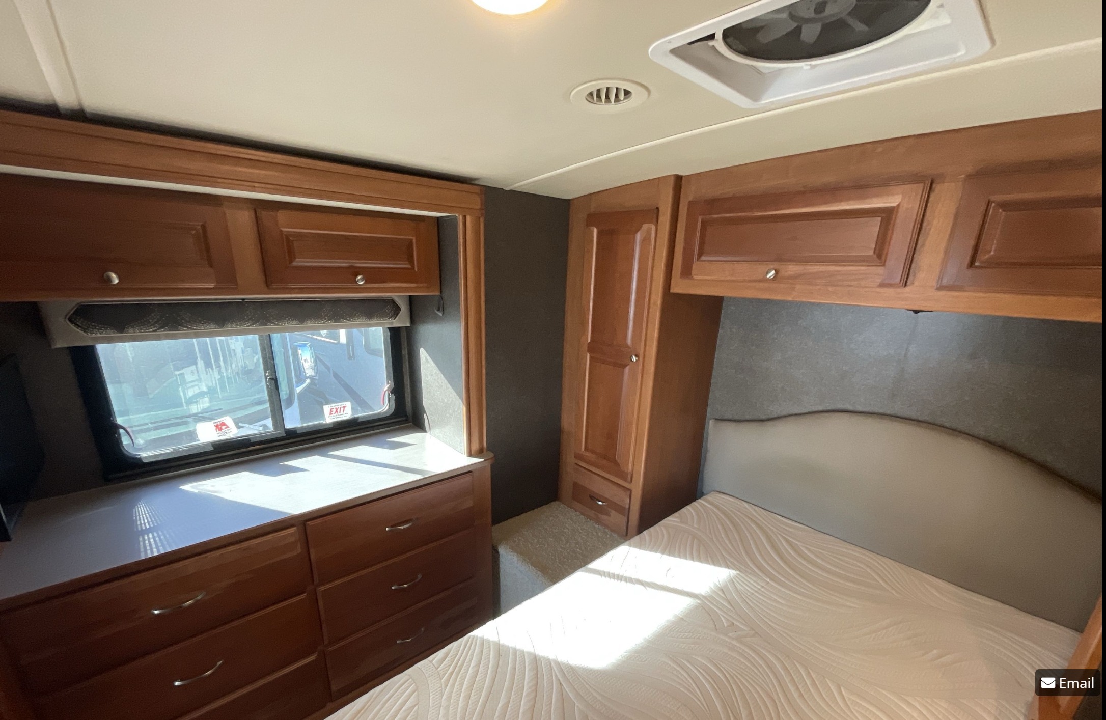 Cozy RV rental bedroom features a comfortable bed, rich wood cabinets, and window for natural light. Ideal for travel.. Winnebago Vista LX 2017