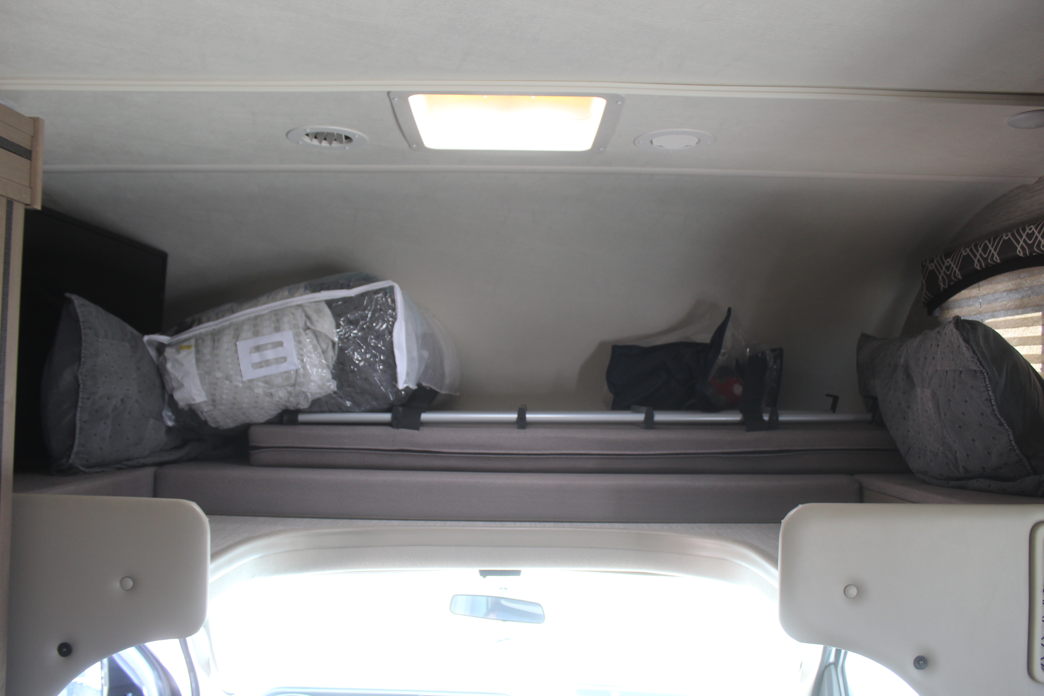RV rental: Cab-over bunk with stored bedding, pillows, and a safety bar. Interior view showing an overhead light.. Thor Chateau 2021
