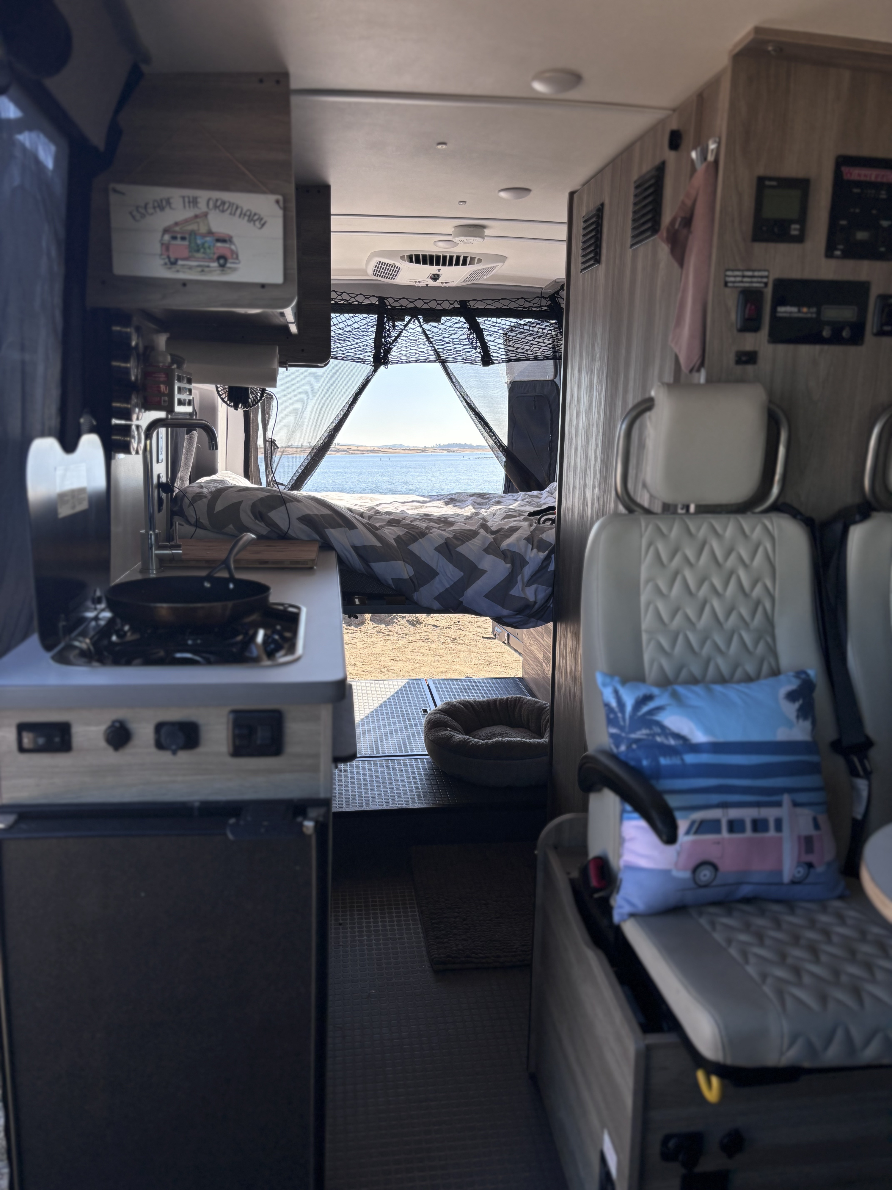 Cozy rv rental interior: kitchen, lake-view bed, and dog bed. 'Escape the Ordinary' van life awaits.. Winnebago Winnebago 2024