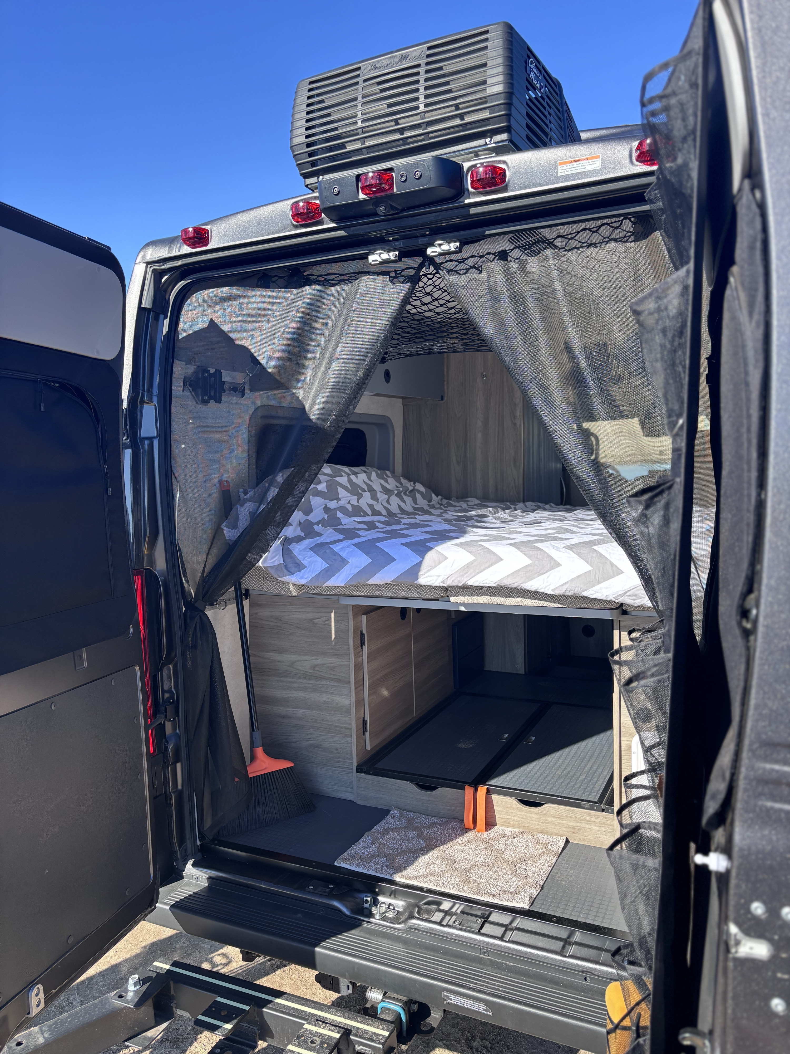 An open RV rental rear reveals a bed, ample storage, and a mesh bug screen for outdoor living comfort.. Winnebago Winnebago 2024