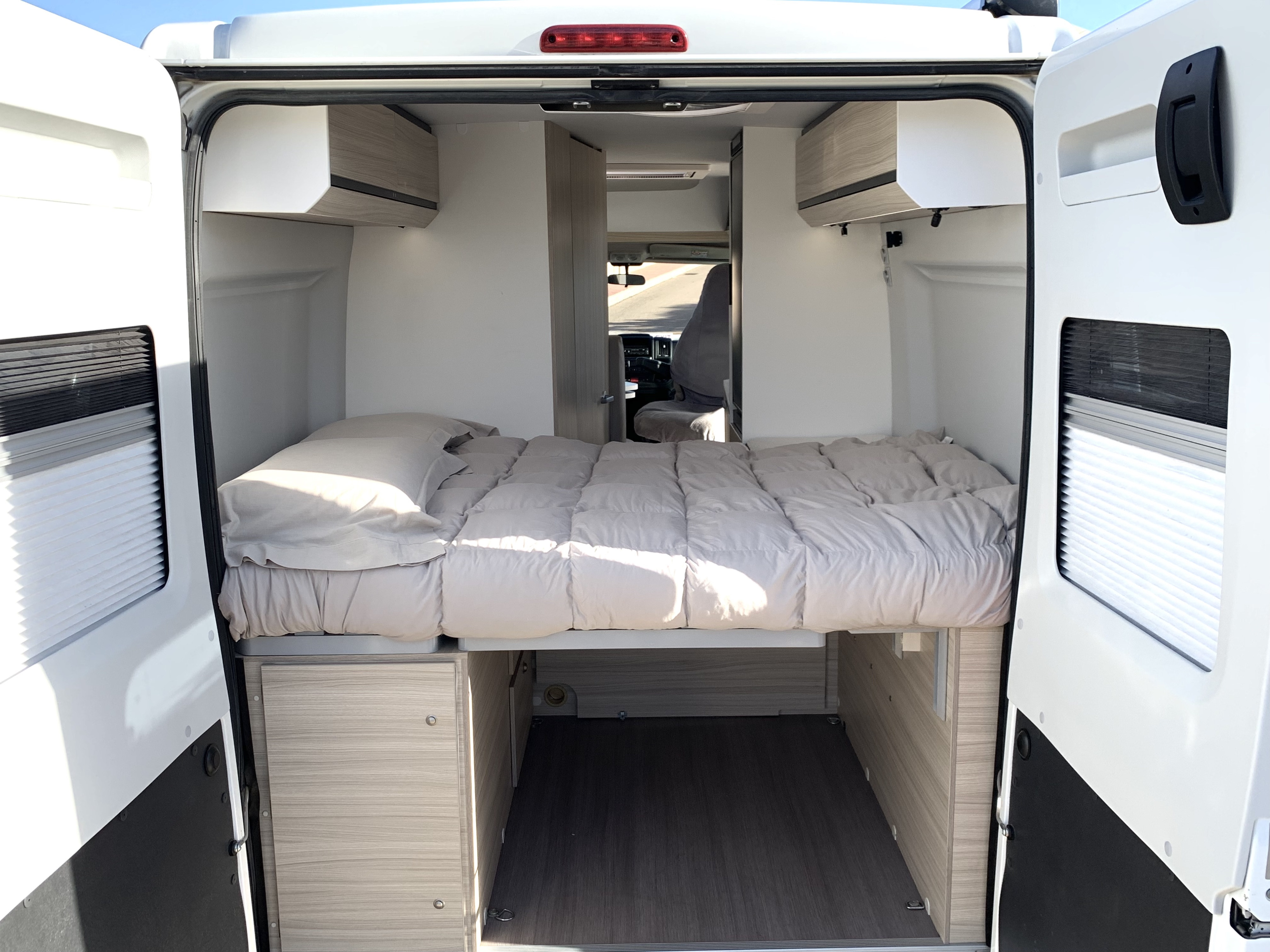 Bright RV rental interior with a comfy bed, overhead storage, and open space below. Ideal camper van layout.. Adria Twin Axess 600 SP 2022