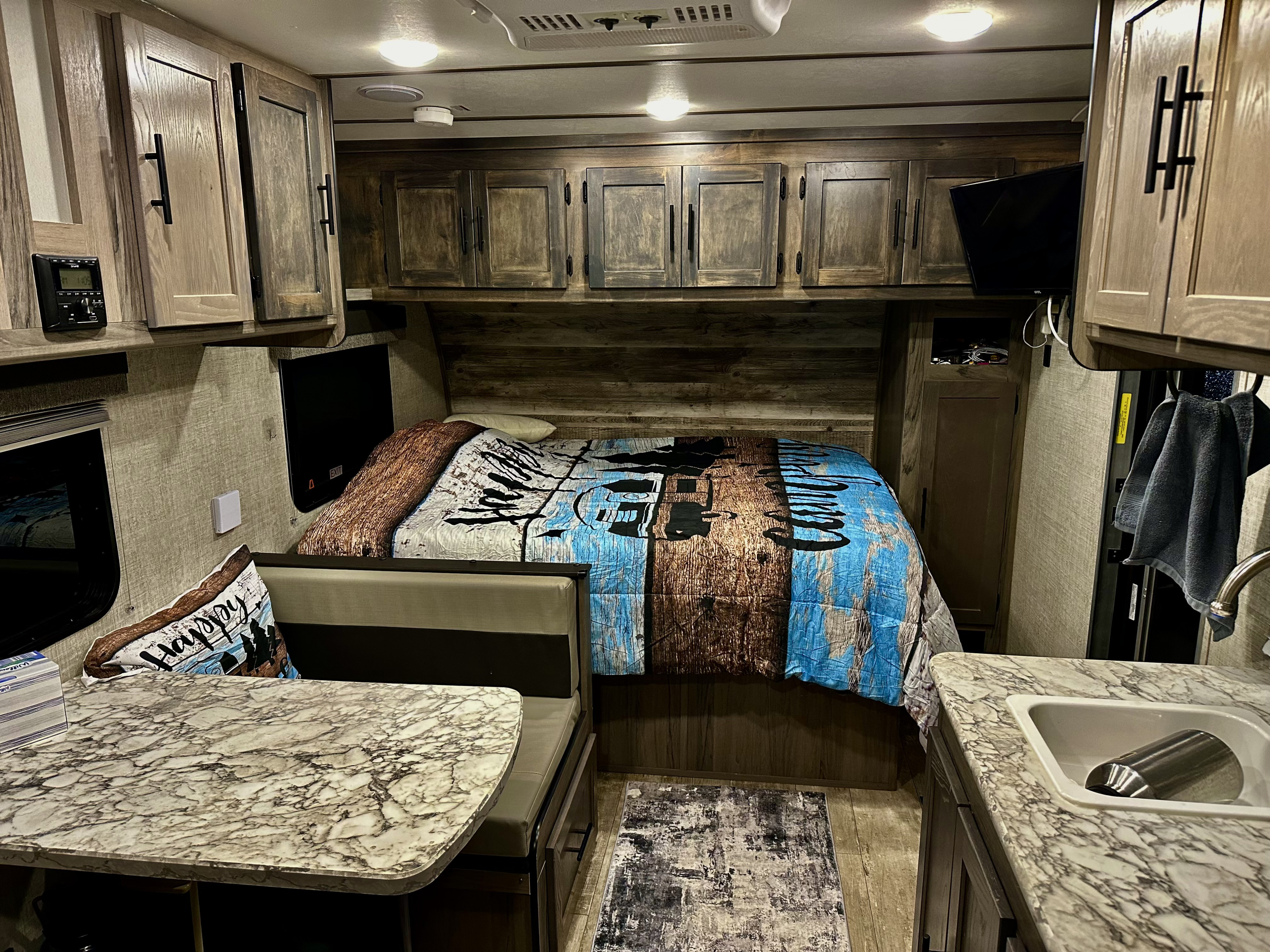 Modern RV rental interior: rustic wood accents, comfy bed, dinette, and kitchen for your next adventure.. Gulf Stream Ameri-Lite Super Lite 2021