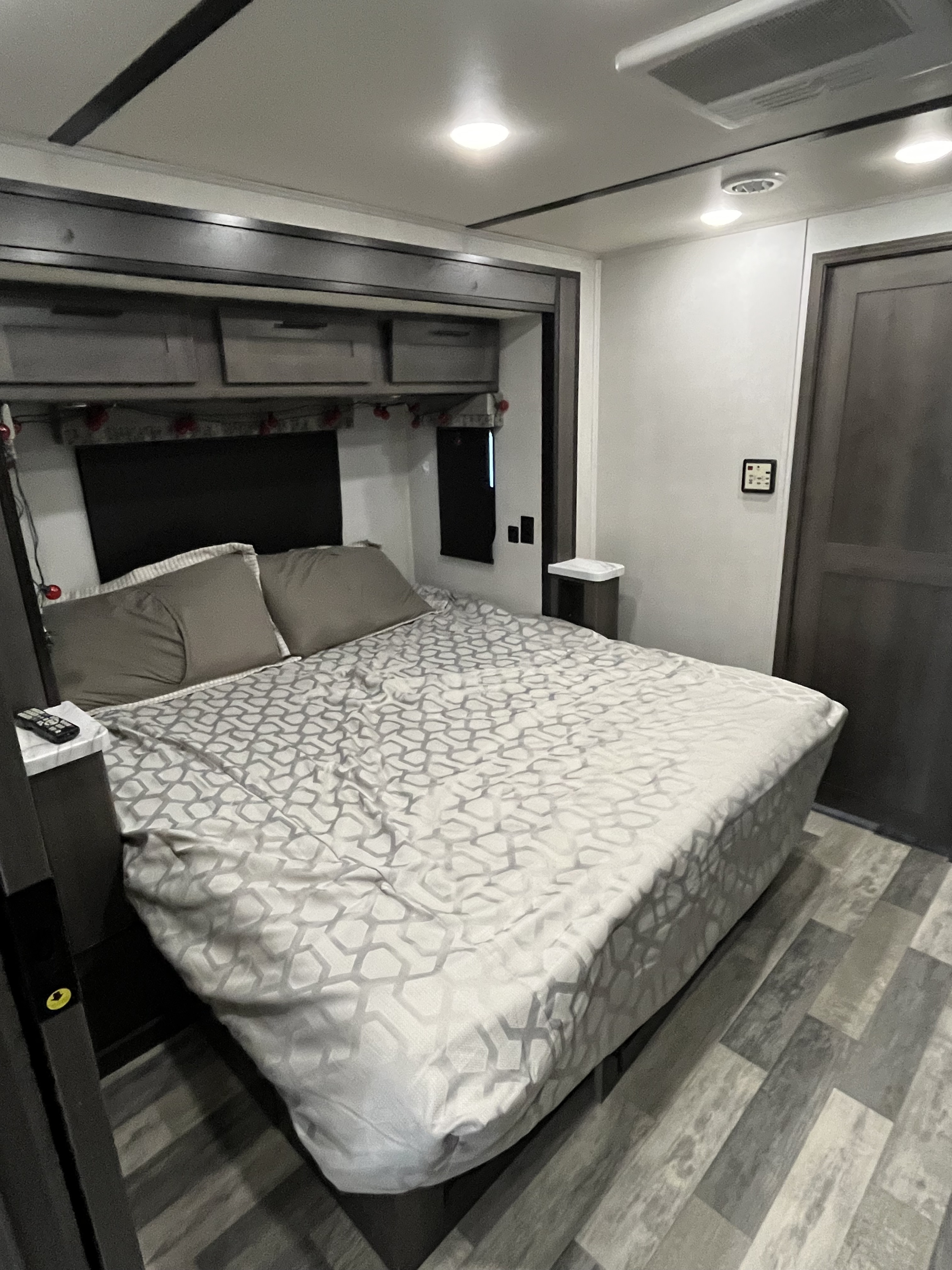 This **RV rental** offers a comfortable bedroom with a patterned bedspread, overhead storage, and vinyl plank flooring.. FR3 FR3 Motorhome 2021