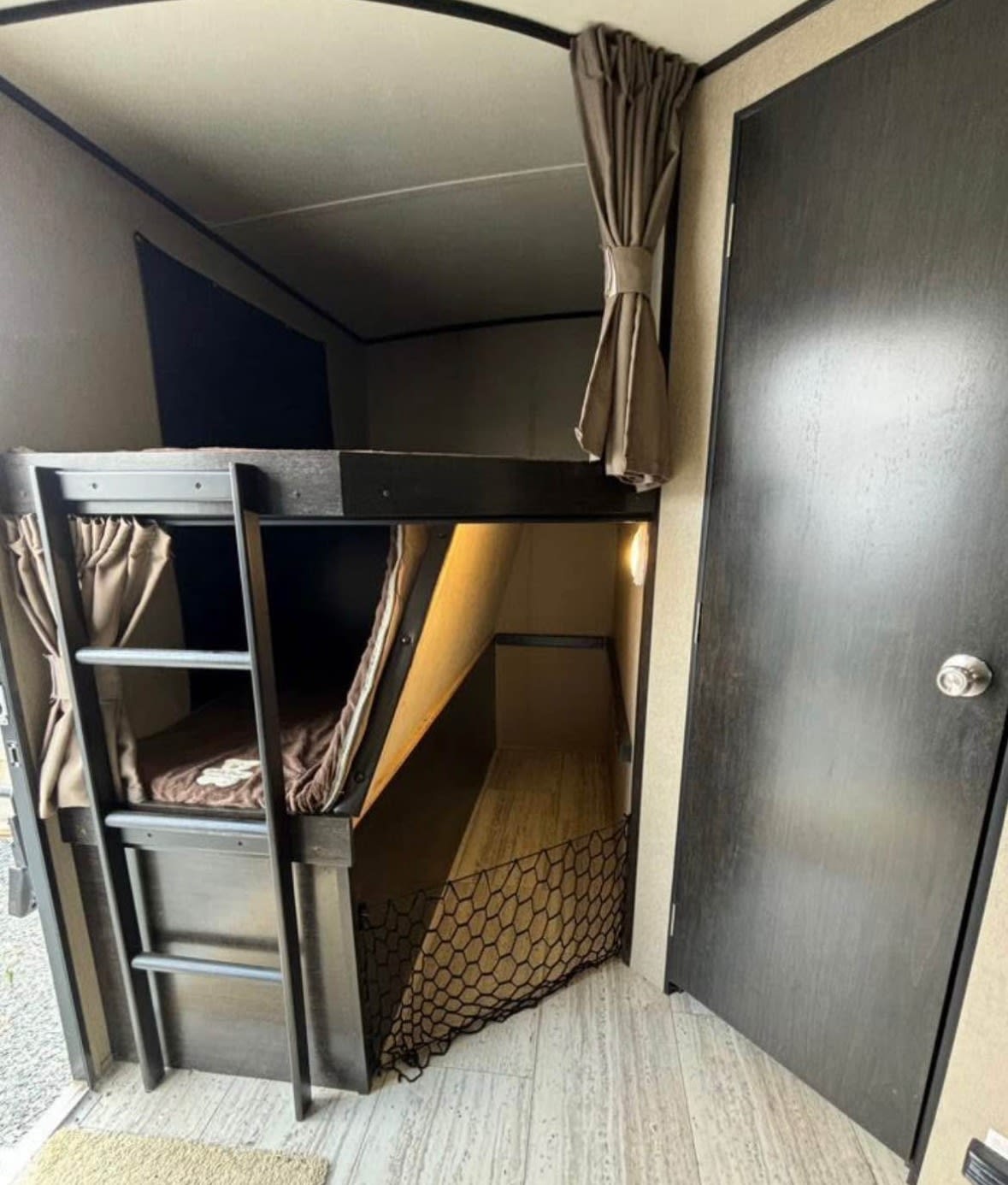 Cozy RV rental interior with bunk beds, ladder, curtains, and safety net, perfect for family sleeping space.. Grand Design Imagine 2018