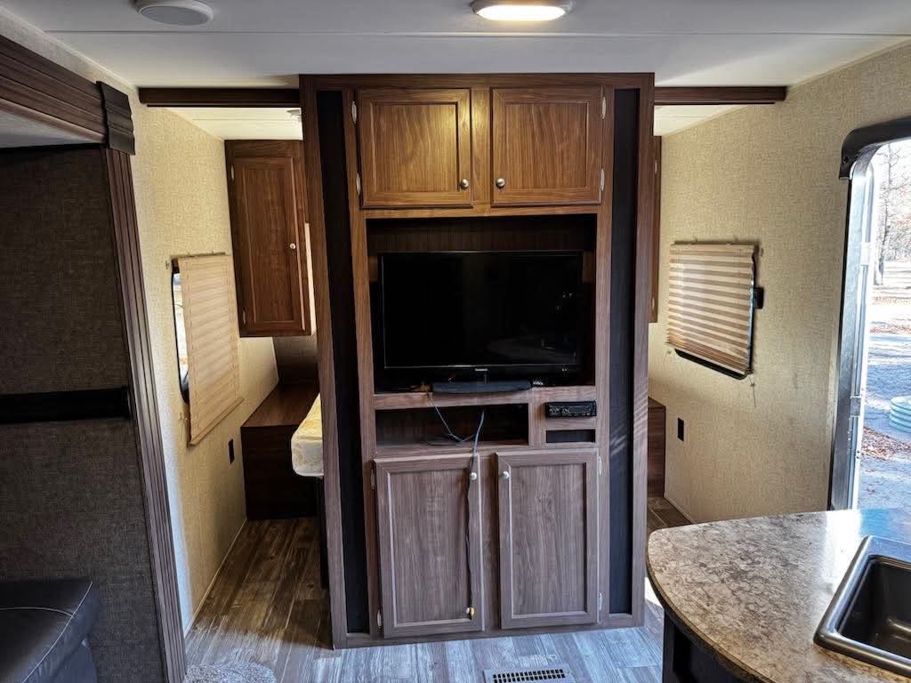 Inside this RV rental: central entertainment unit, two cozy bedroom areas with windows, and a functional kitchen counter.. Heartland RVs Pioneer 2016