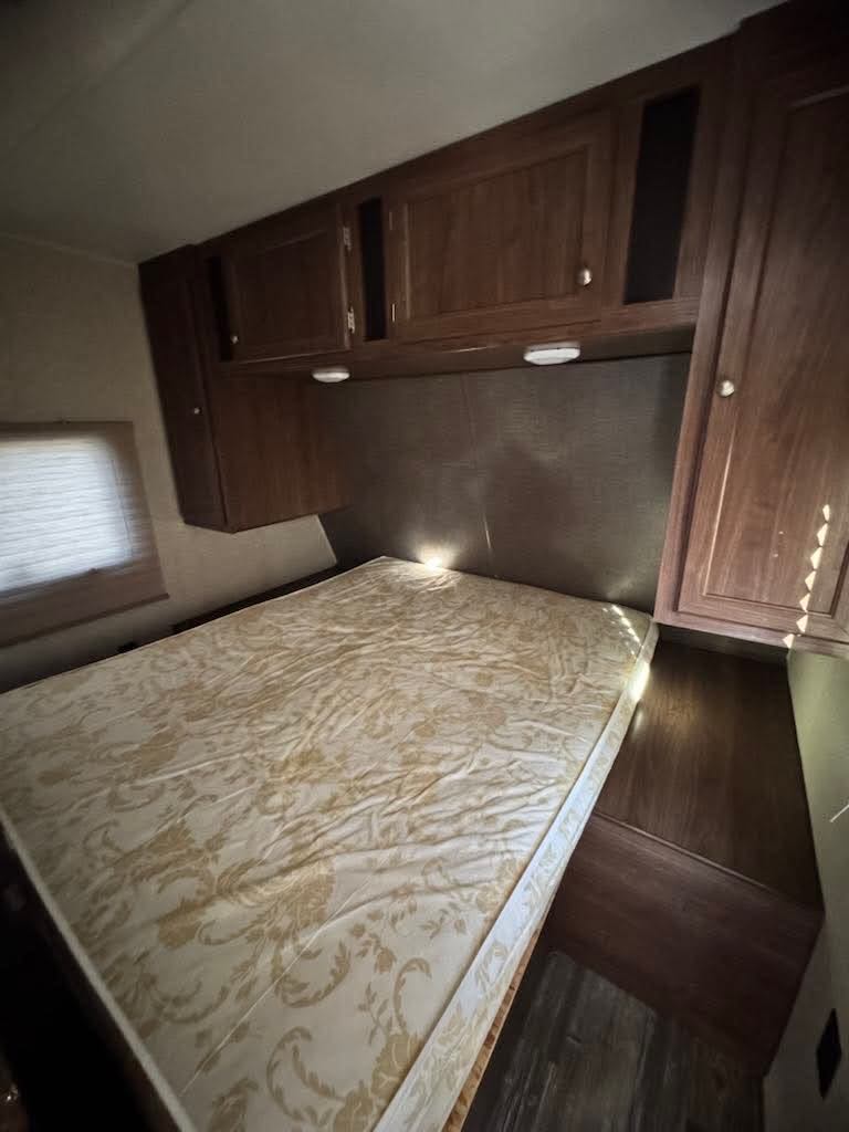 RV rental: A compact bedroom with a patterned mattress, overhead cabinets, and built-in side storage.. Heartland RVs Pioneer 2016