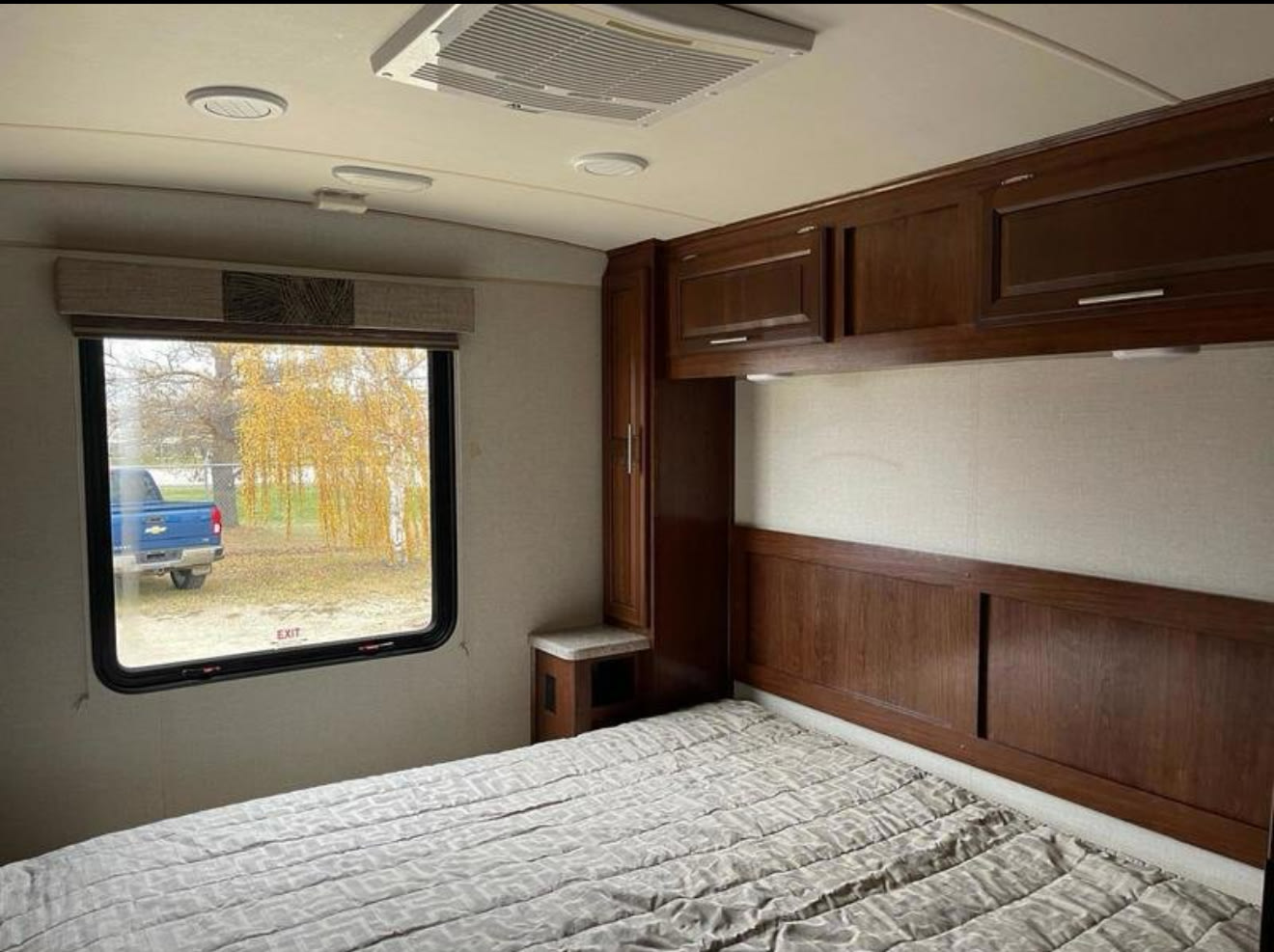 Comfortable RV rental bedroom: large bed, wood cabinets, window showing fall trees & blue truck outside. Ready for adventure.. FR3 FR3 Motorhome 2017