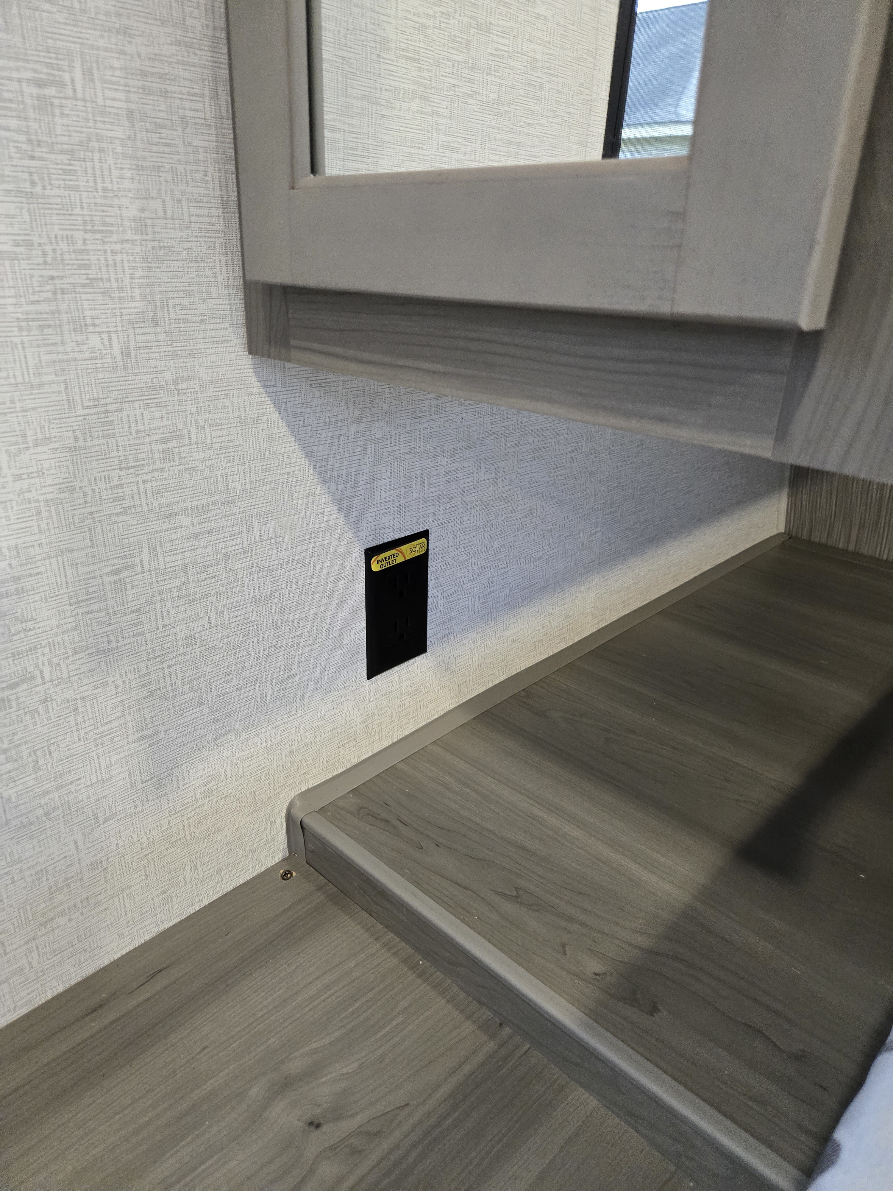 RV rental interior with an 'INVERTED OUTLET' (Solar Flex labeled) on the wall above a wood-grain counter.. Keystone Hideout 240BH 2025