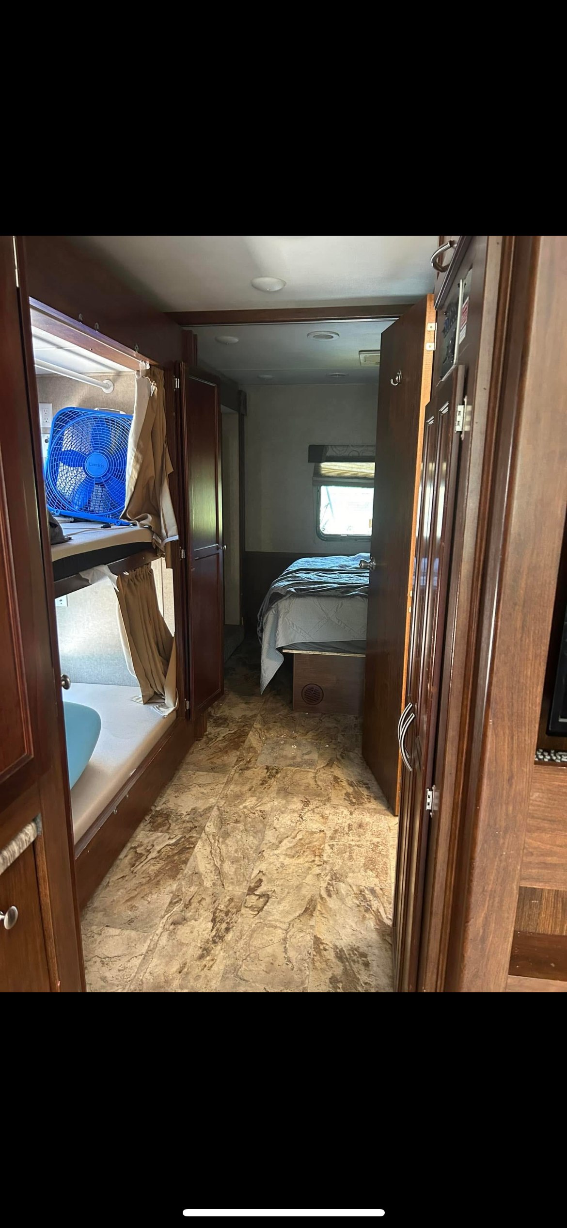 This RV rental's interior shows bunk beds with a blue fan on the left, leading to the bedroom on the right. A functional mobile living space.. Forest River Coachmen Pursuit 2017