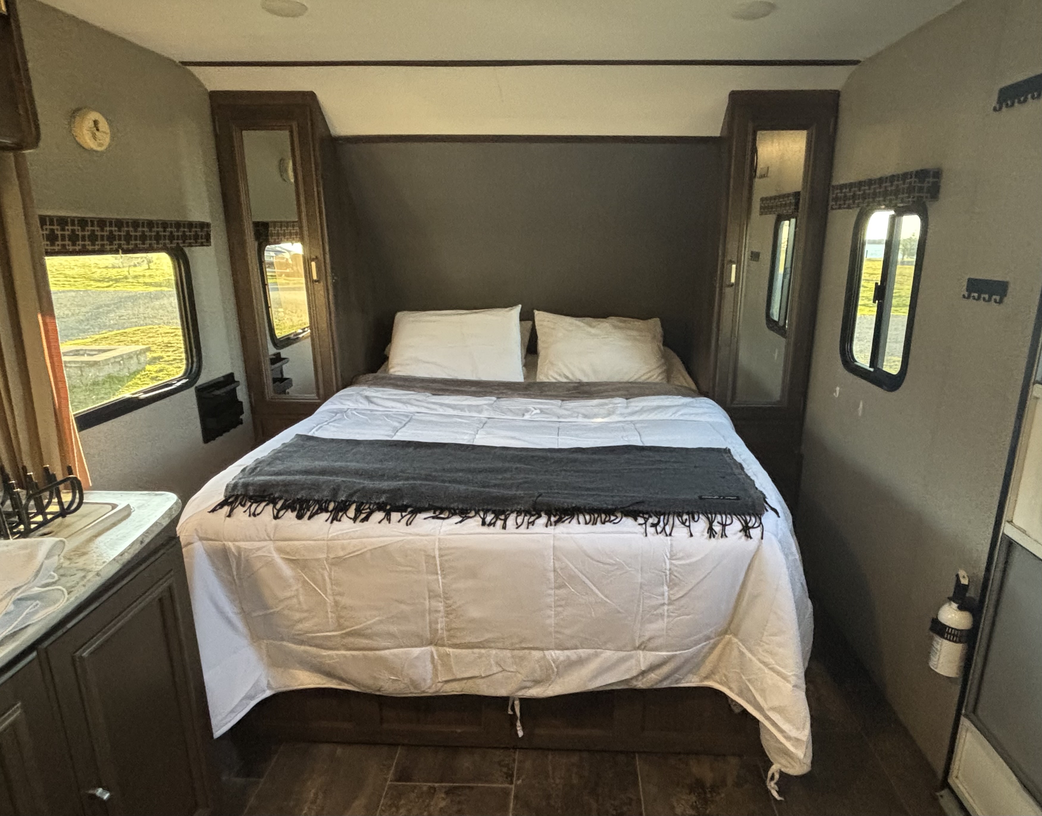 This RV rental features a cozy bedroom with a spacious bed, built-in storage, and bright windows, perfect for your travels.. Keystone RV Passport Ultra Lite 2019