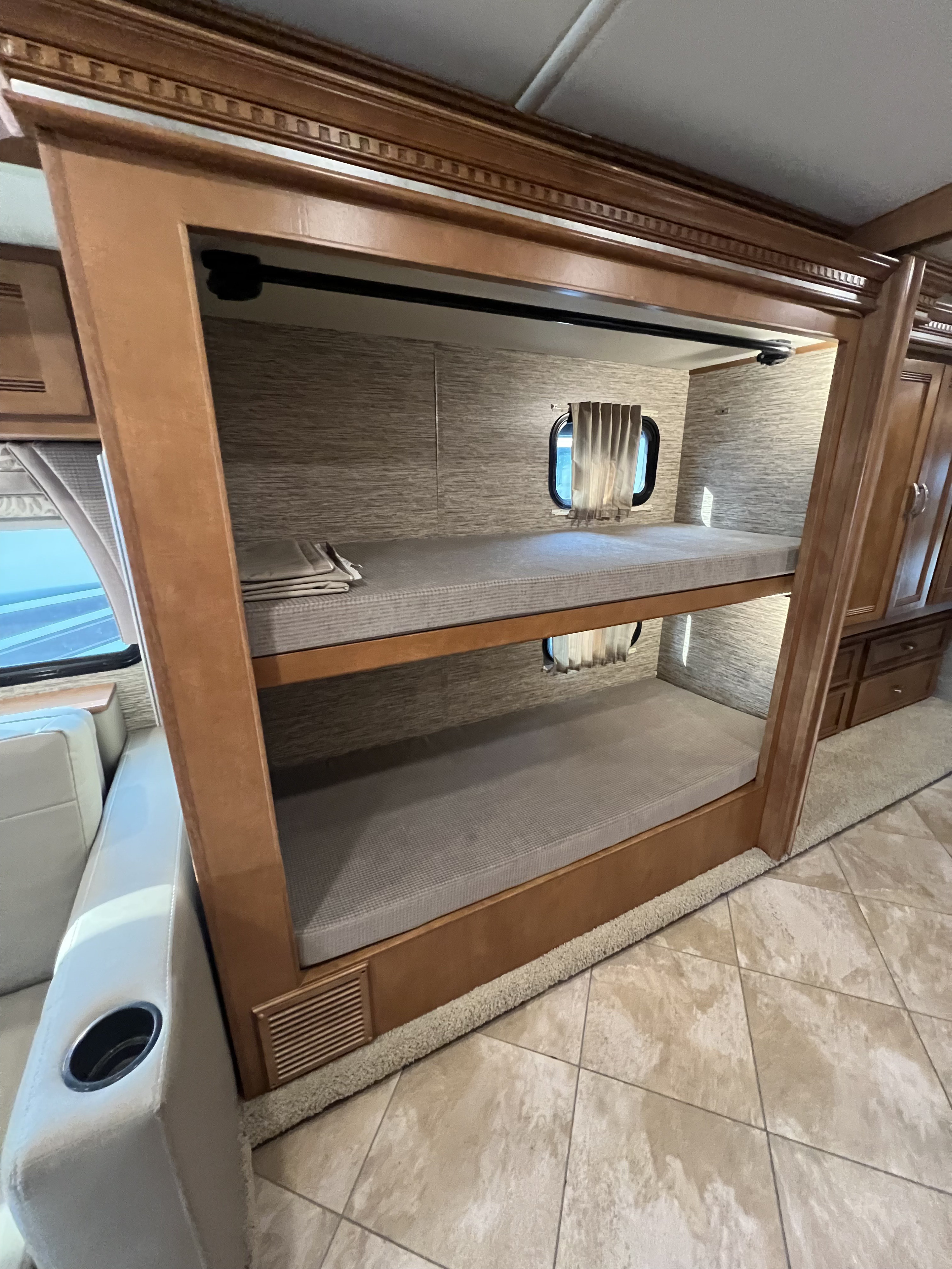 This RV rental showcases a comfortable and compact bunk bed area, complete with privacy windows, ideal for family trips.. Winnebago Forza 2019