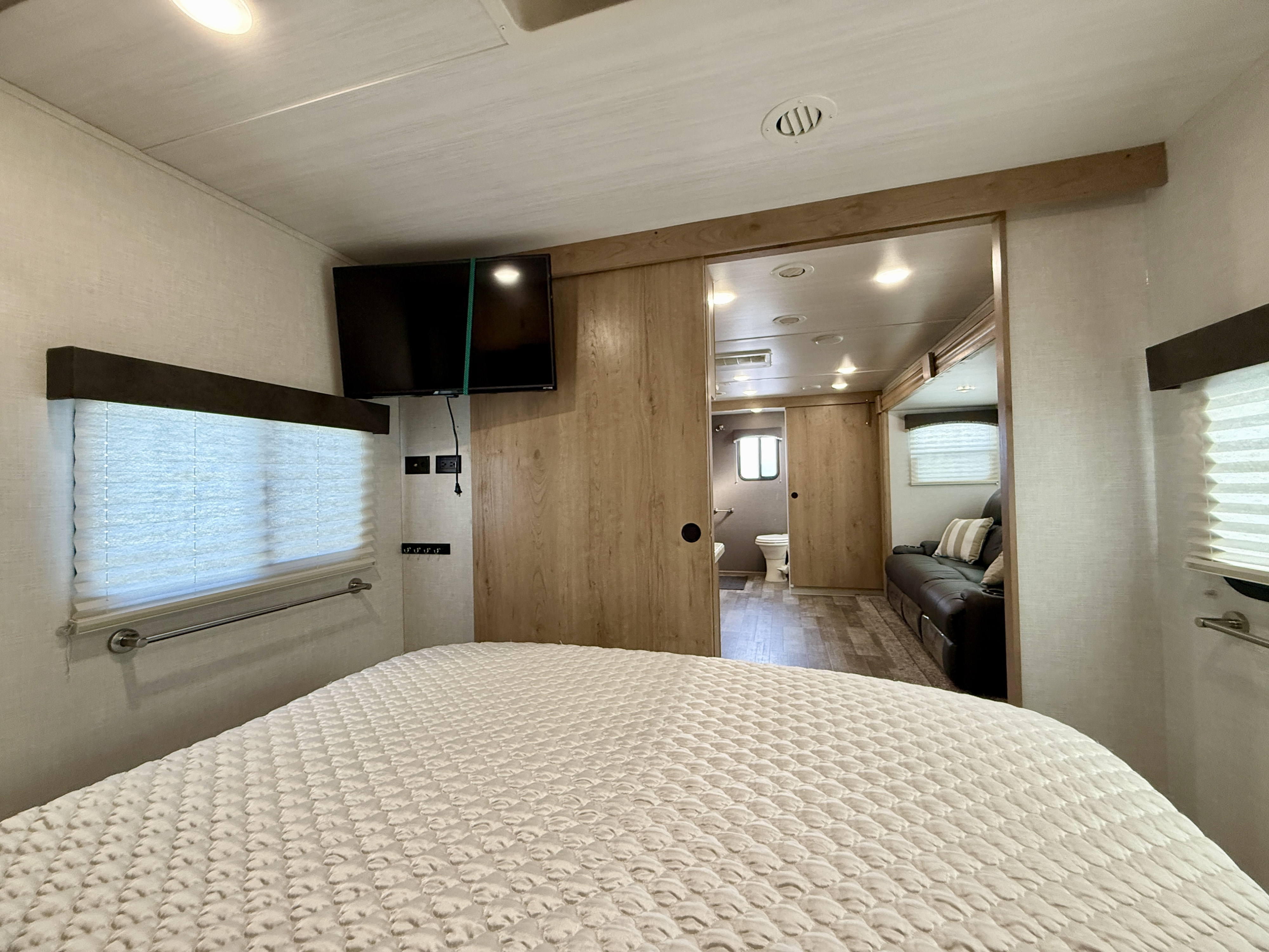 RV rental bedroom offers comfort with a TV, window, and access to living and bath areas.. Winnebago Micro Minnie 2020
