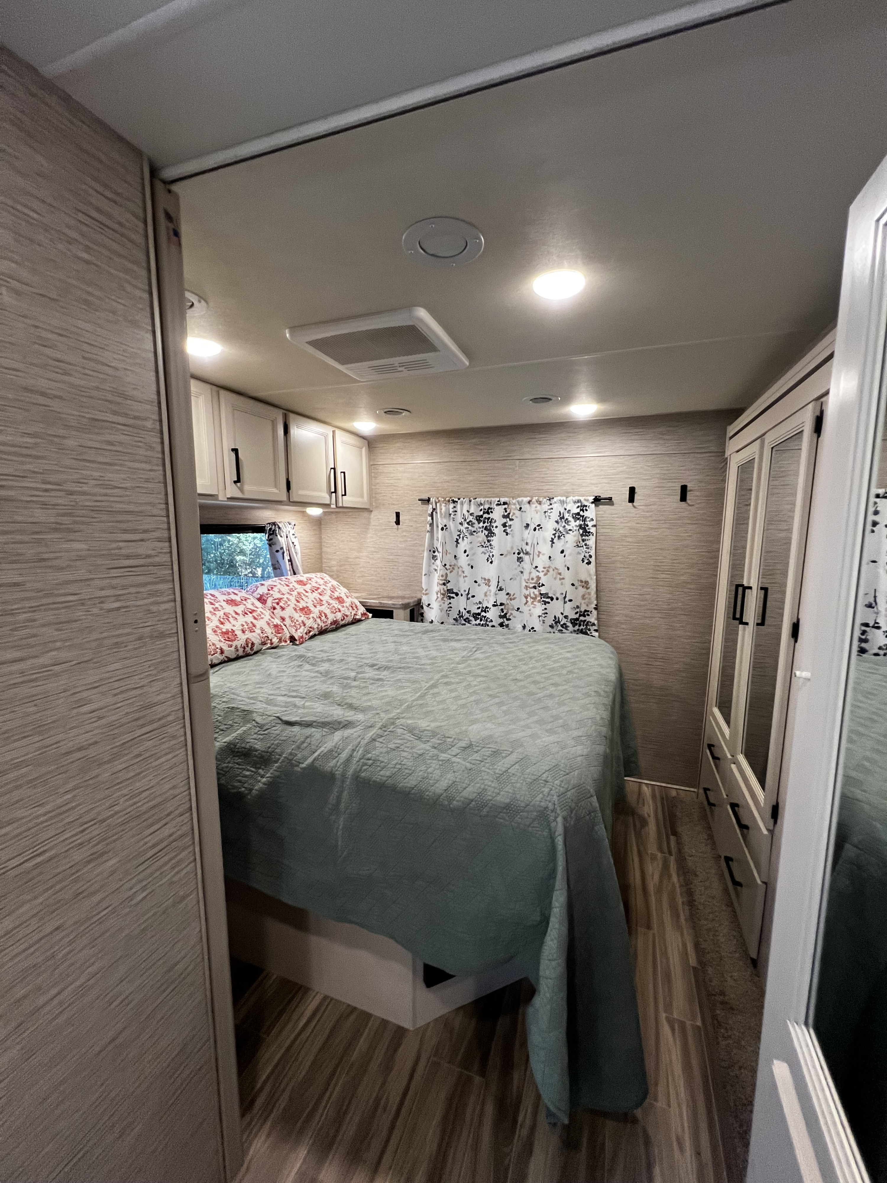 Cozy RV rental bedroom featuring a bed, overhead cabinets, and a spacious mirrored closet. Ideal for comfortable travel.. Thor Four Winds 2022