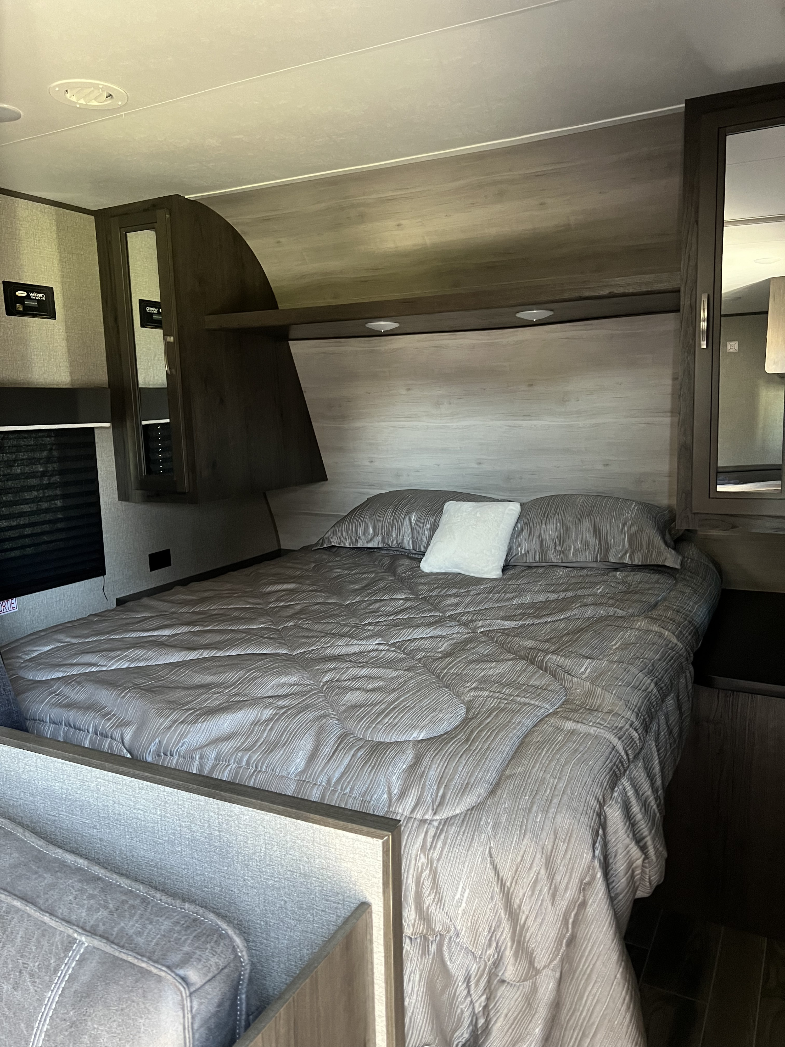 Comfortable RV rental bedroom with a full bed, gray bedding, built-in overhead storage, reading lights, and wall controls.. Jayco Jay Flight SLX Rocky Mountain Edition 2020