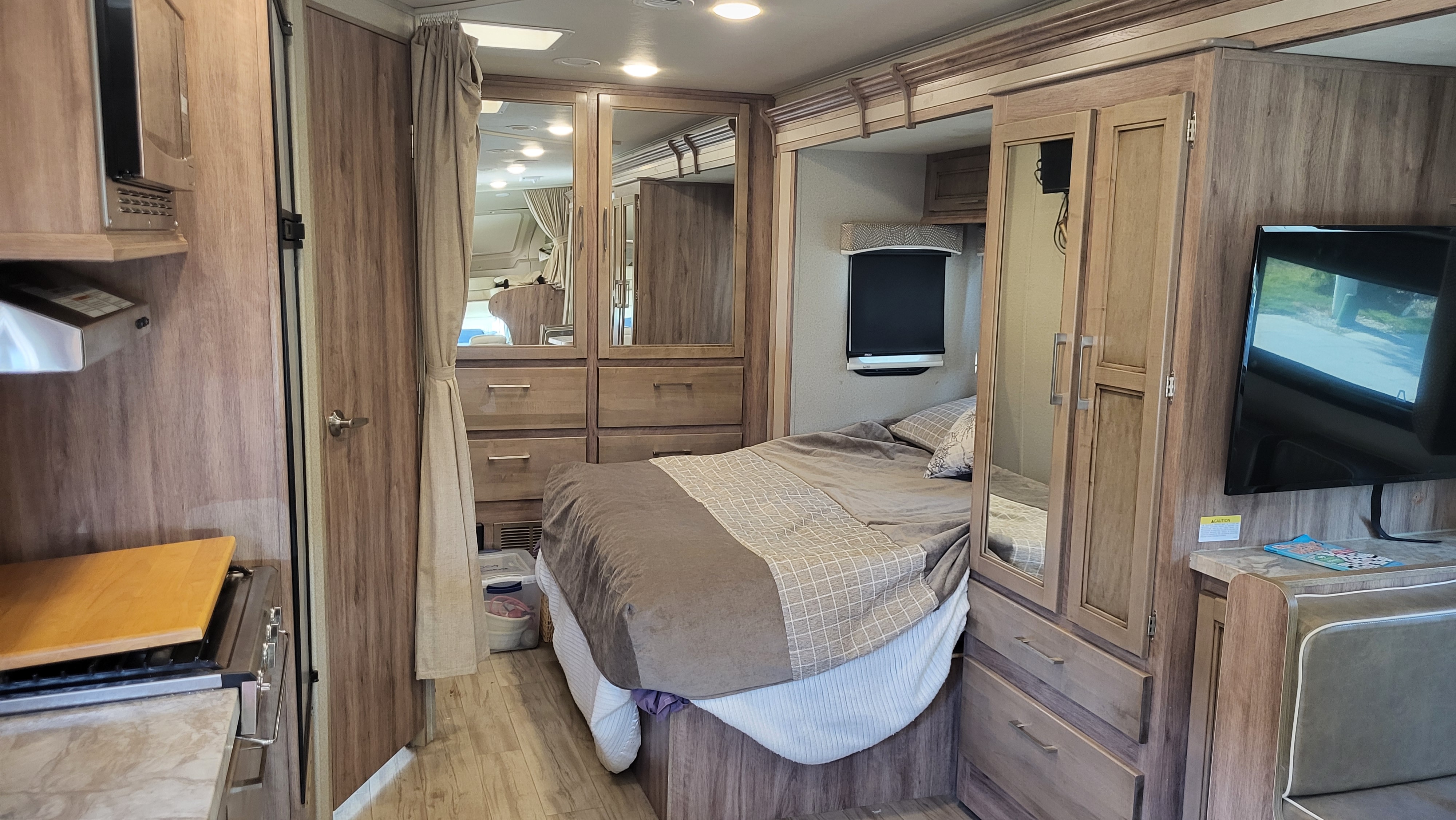Step inside this RV rental, featuring a full bed with storage, compact kitchen with microwave/stove, and a TV for your comfort.. Entegra Coach Odyssey 2019