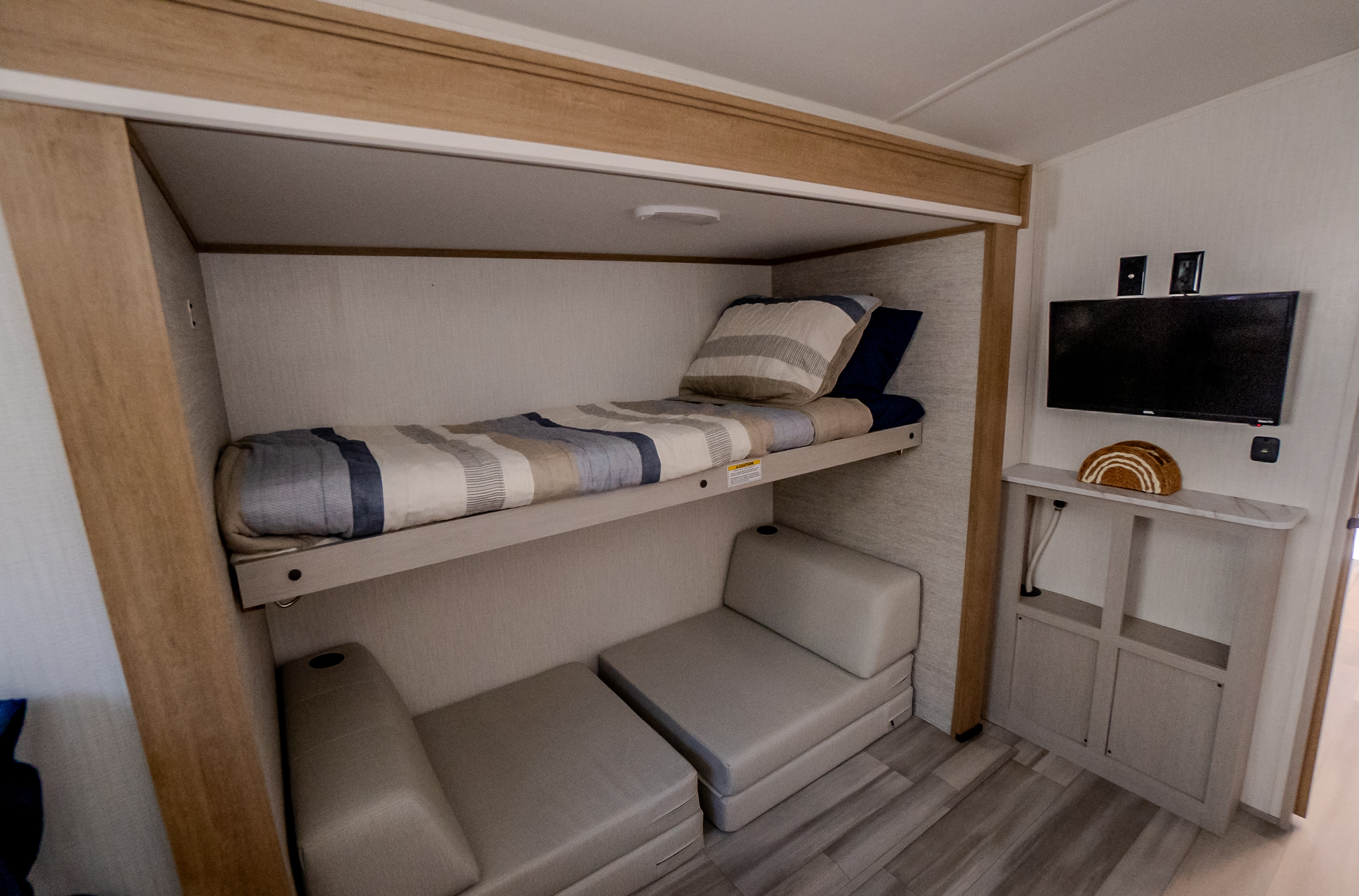 RV rental with modern bunk beds & convertible lower seating area, plus a wall-mounted TV. Compact and functional.. Cruiser RV Embrace 2024