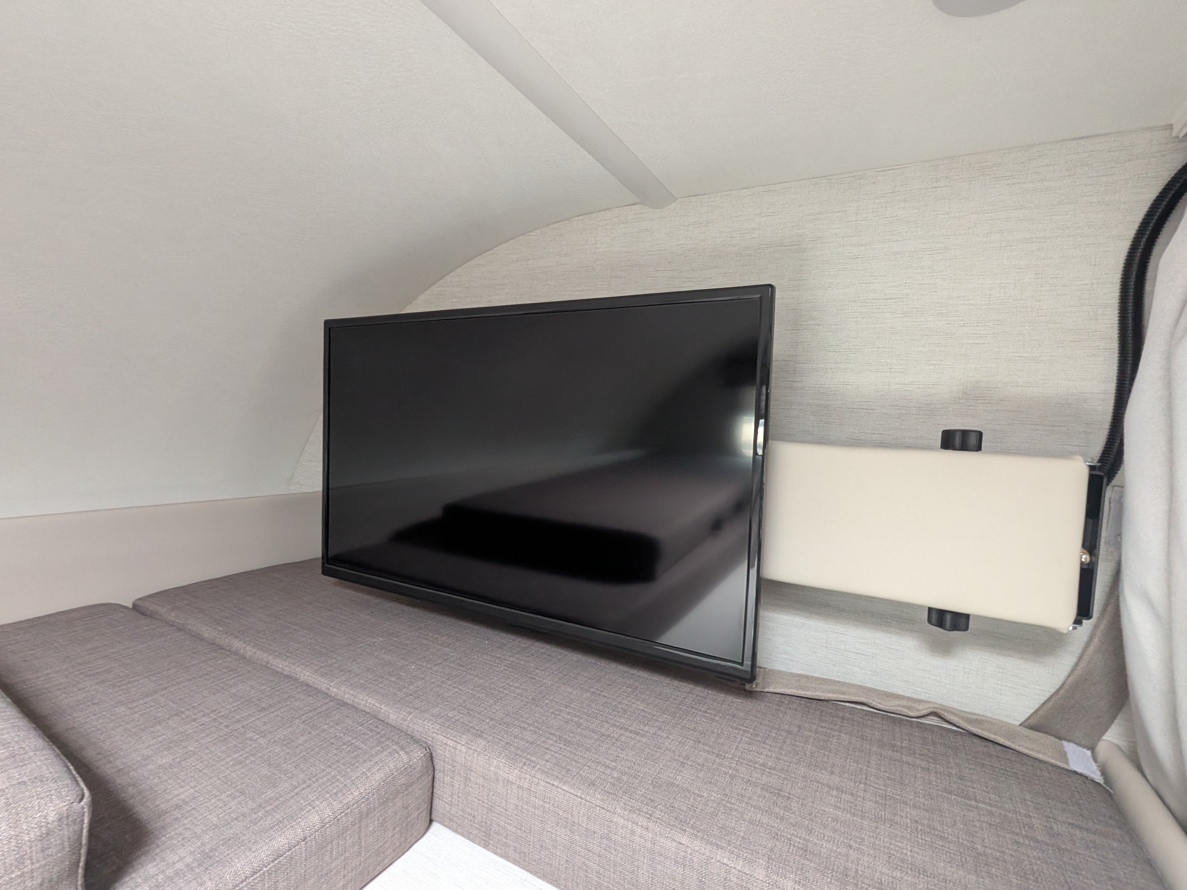 RV rental interior features a flat-screen TV on an adjustable mount, perfect for entertainment above cozy seating/bed cushions.. Thor Motor Coach Chateau 2025