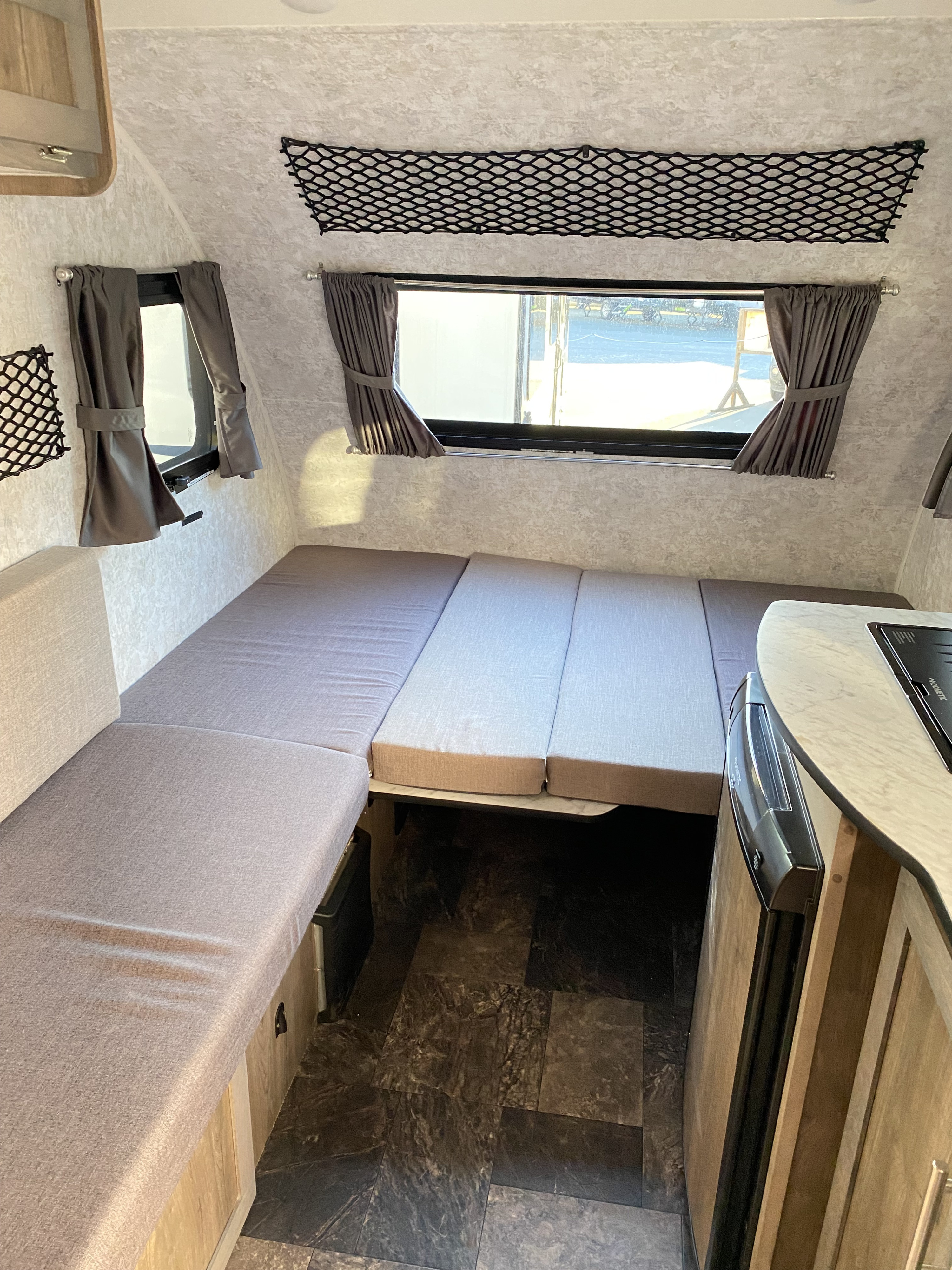 Cozy RV rental interior: versatile seating converts to a bed, plus a compact kitchen and practical storage nets.. Roulettes Prolite Plus S 2024