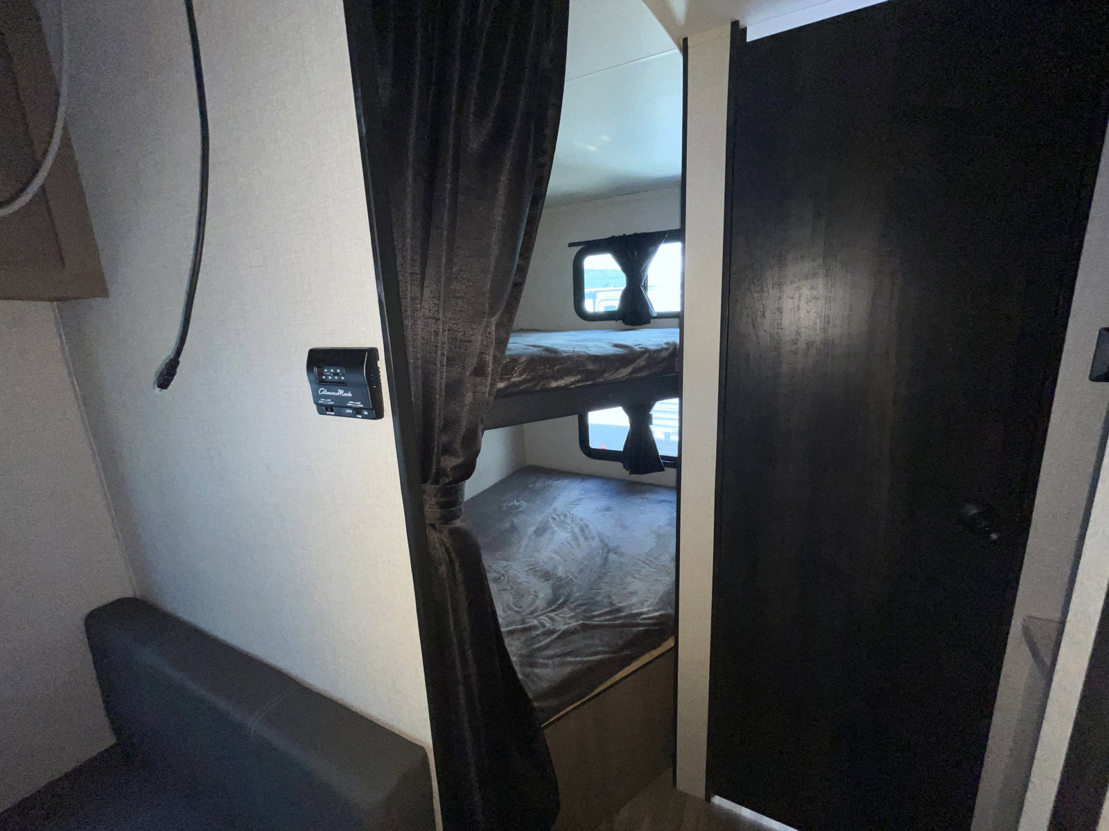 RV rental bunkhouse interior: Twin bunk beds with windows, climate control panel, and sofa seating. Ideal for family trips.. Highland Ridge RV Open Range 2022