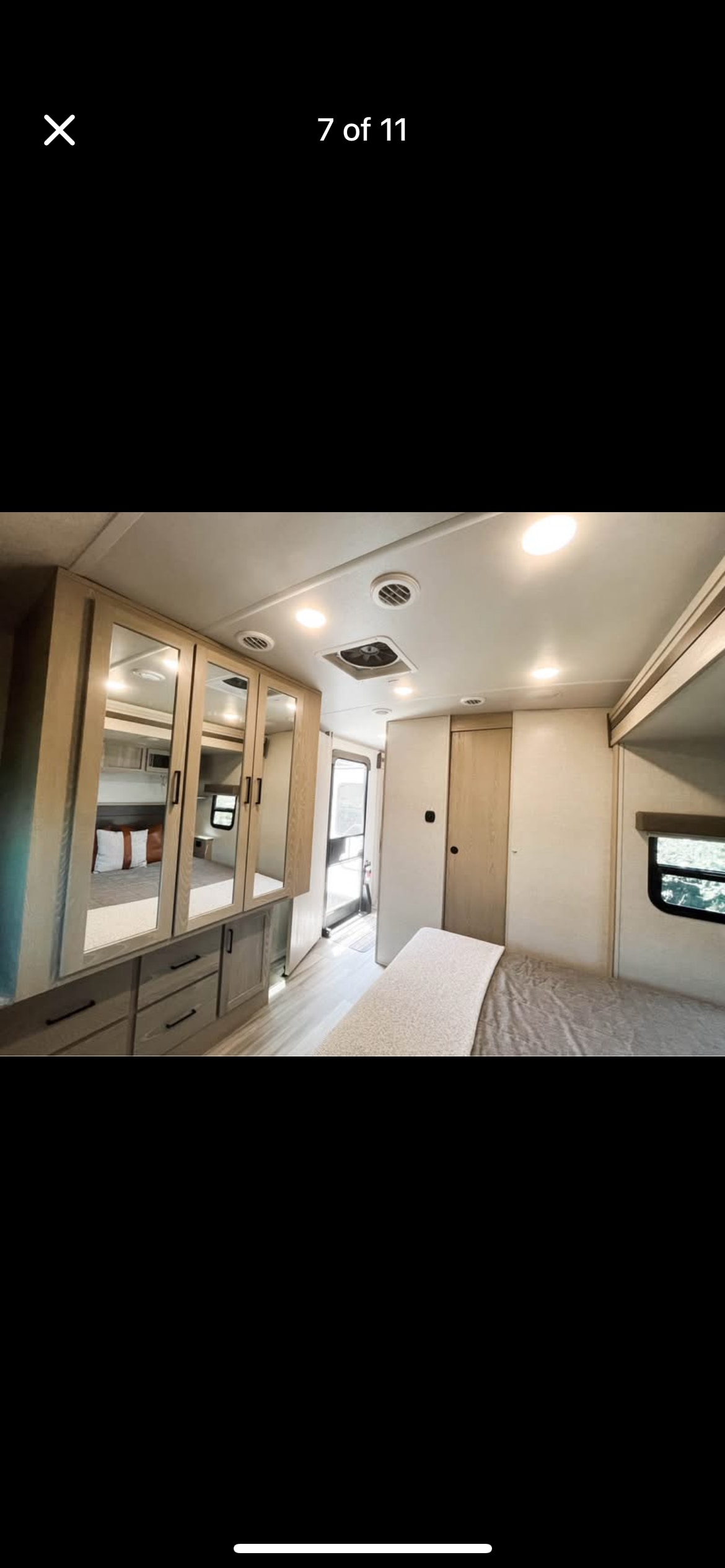 Spacious RV rental bedroom interior featuring modern light wood cabinetry with mirrored doors, comfortable bed, and window.. Forest River Rockwood Signature 2021
