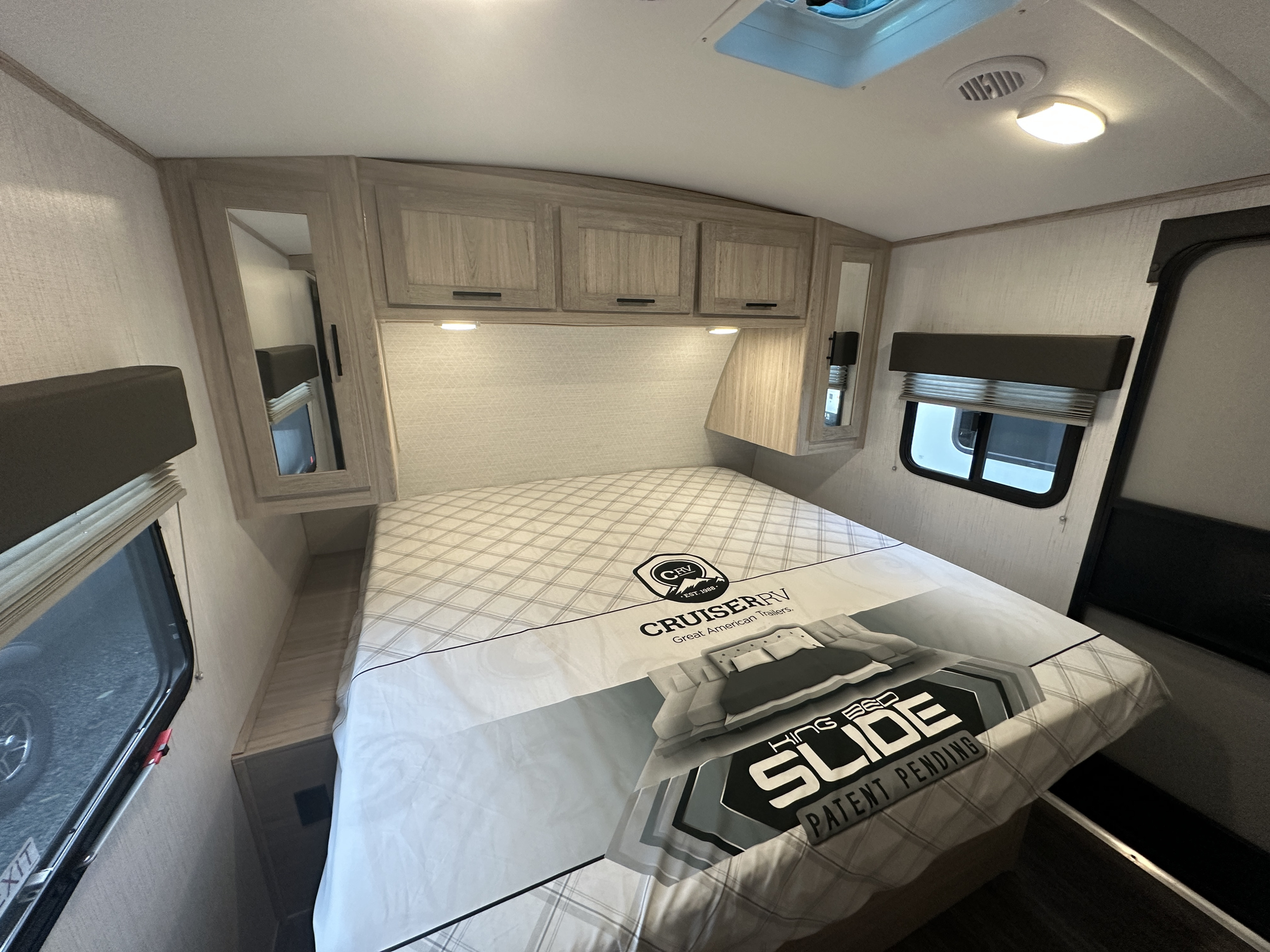 Spacious RV rental bedroom featuring a King Bed Slide, built-in cabinets, and large windows.. Cruiser RV Shadow Cruiser 2022