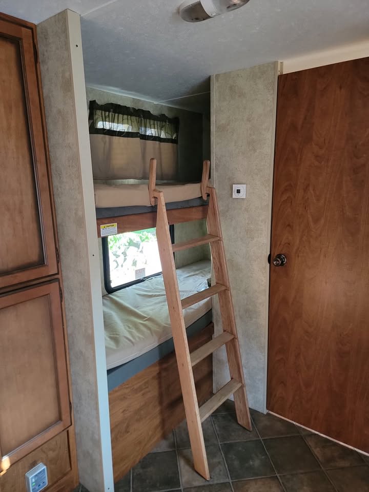 RV rental interior shows bunk beds with a ladder, window, and cabinets, offering comfortable sleeping.. Keystone RV Passport Ultra Lite 2012