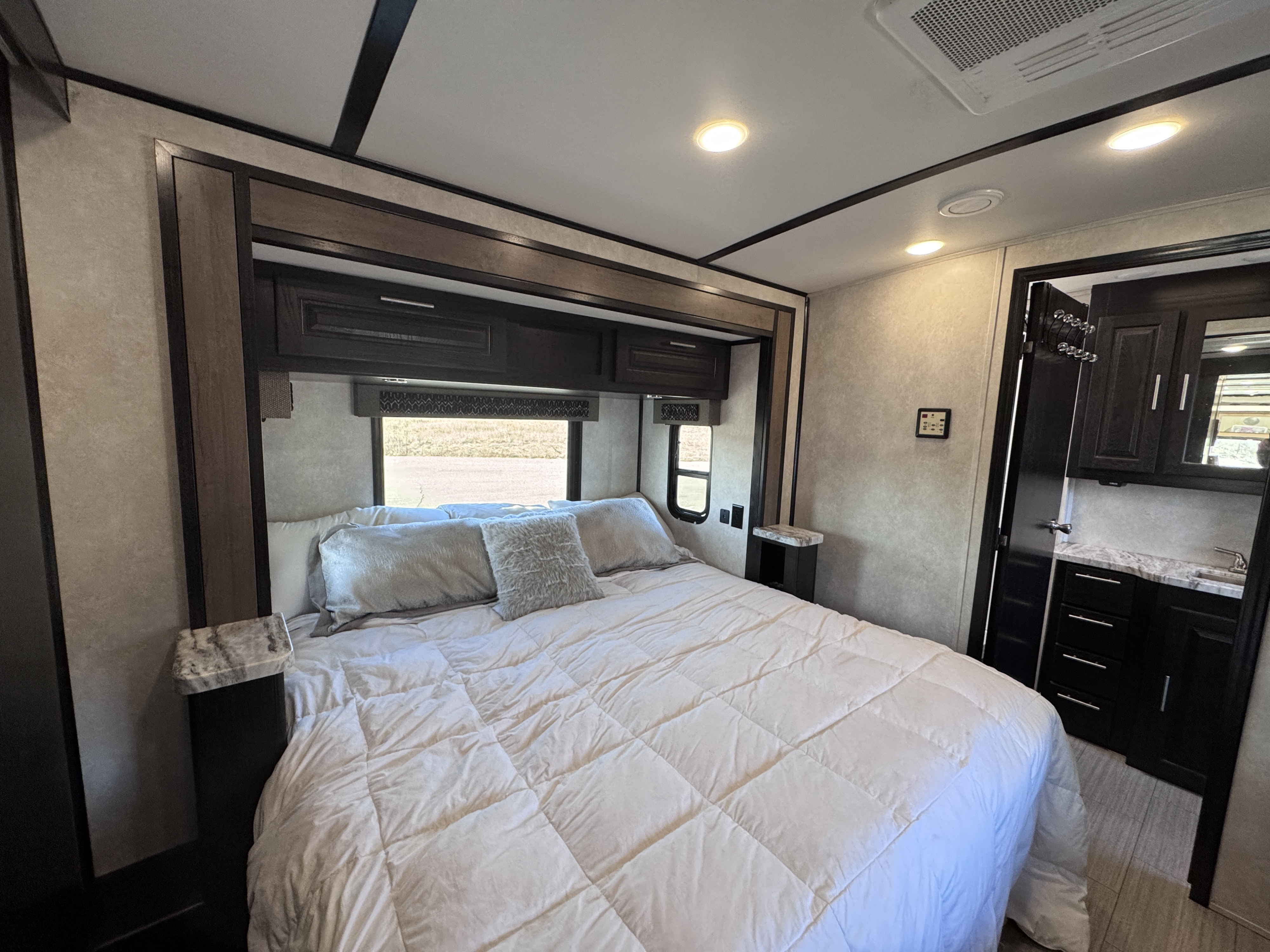 Step inside this inviting RV rental bedroom, featuring a large bed, built-in overhead storage, and a convenient vanity area.. FR3 FR3 Motorhome 2021