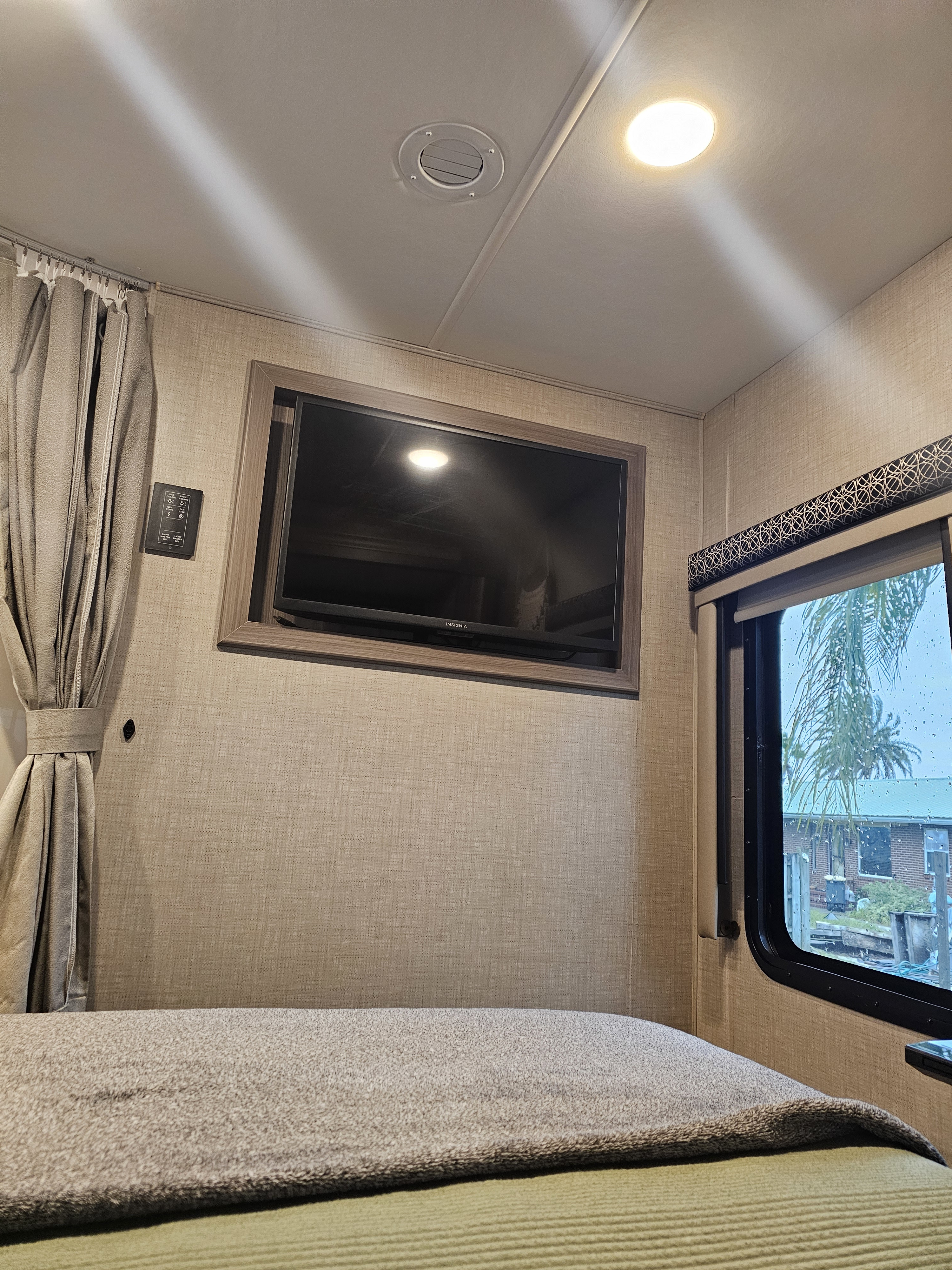 RV rental: Comfortable bedroom featuring a mounted TV, cozy bed, and window overlooking the outside.. Thor Tiburon 2023