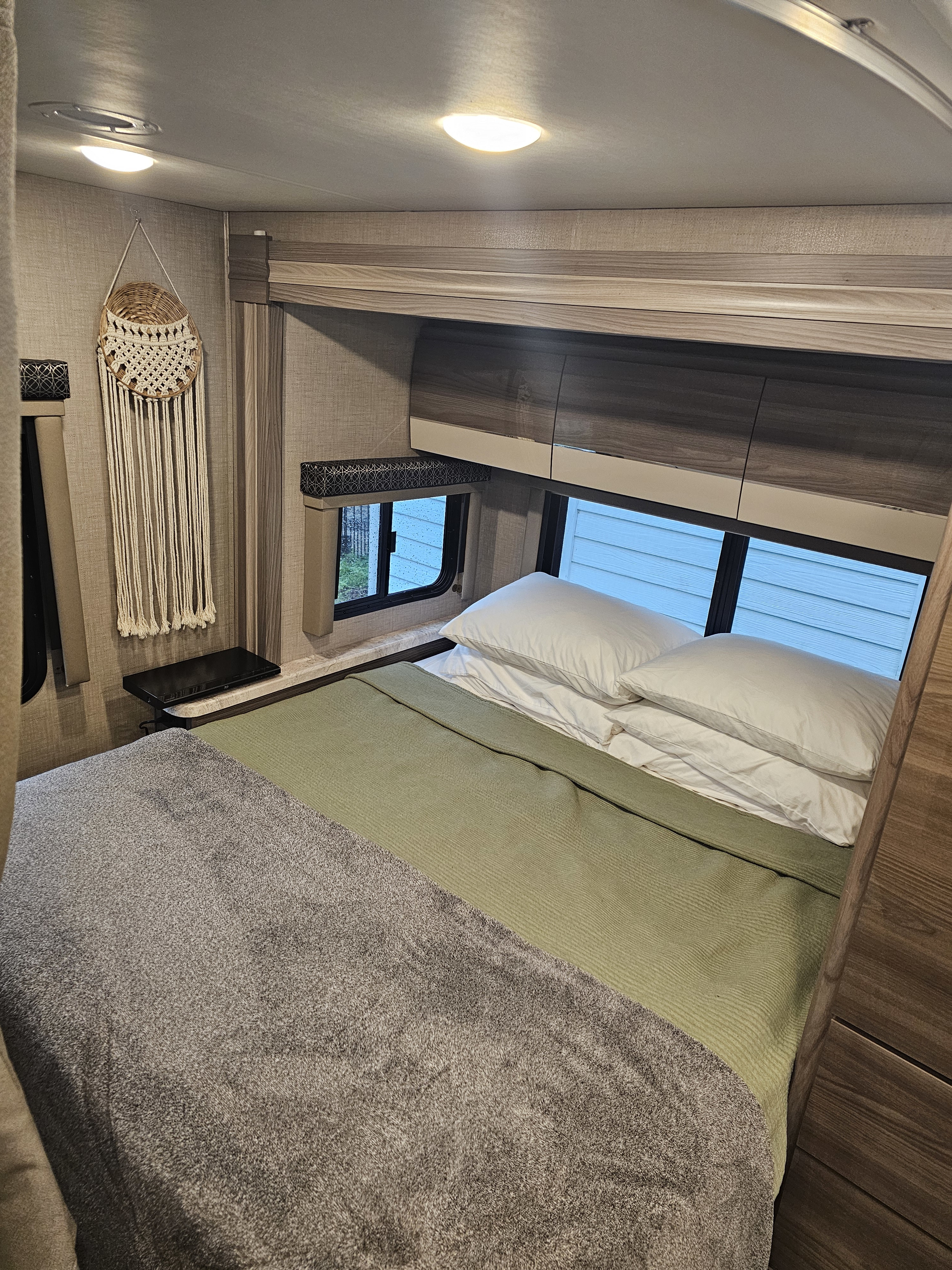 Cozy RV rental bedroom: a warm retreat with a soft bed, overhead storage, and window view.. Thor Tiburon 2023
