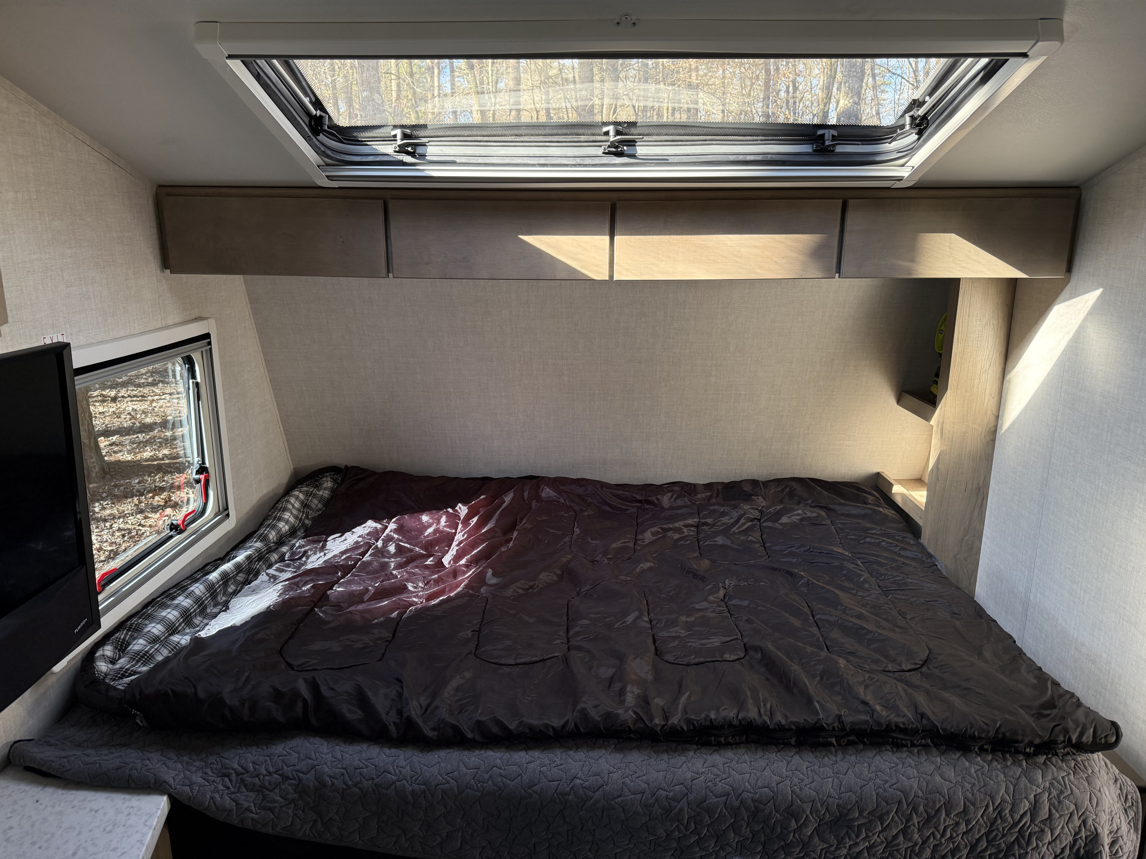 Queen bed beneath a large skylight inside the camper