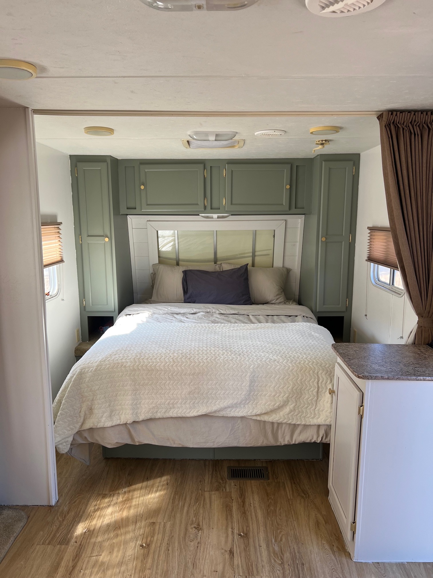 Step inside this cozy, renovated RV rental bedroom, featuring a large bed, sage green cabinets, and wood-look flooring.. Aljo Aljo Trailer 2008