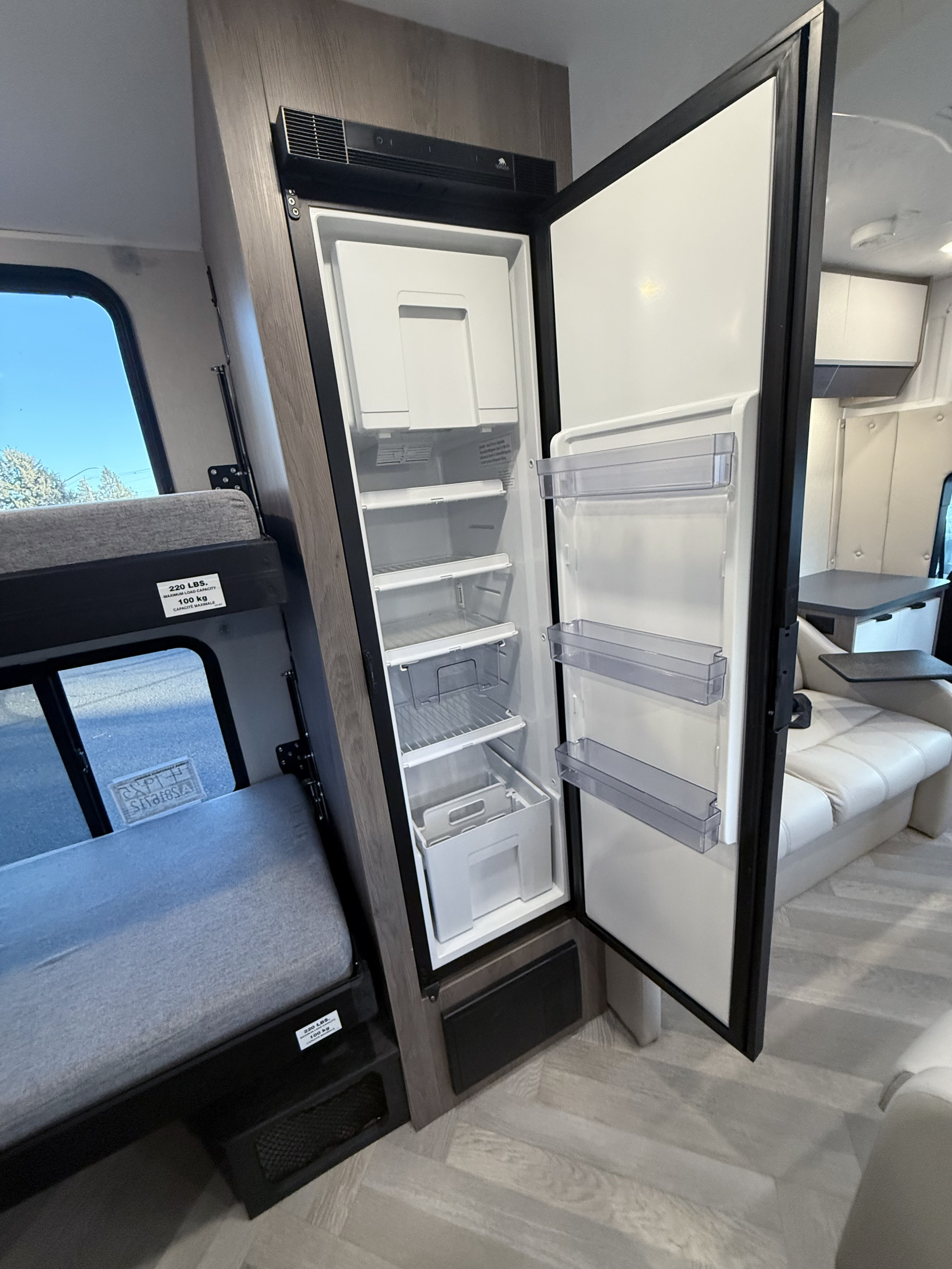 Inside an RV rental: a full-size refrigerator with freezer, a 220 lbs capacity bunk bed, and a comfortable lounge area.. Coachmen cross trail, 20 Bunkhouse, Camper Van, Class B 2024