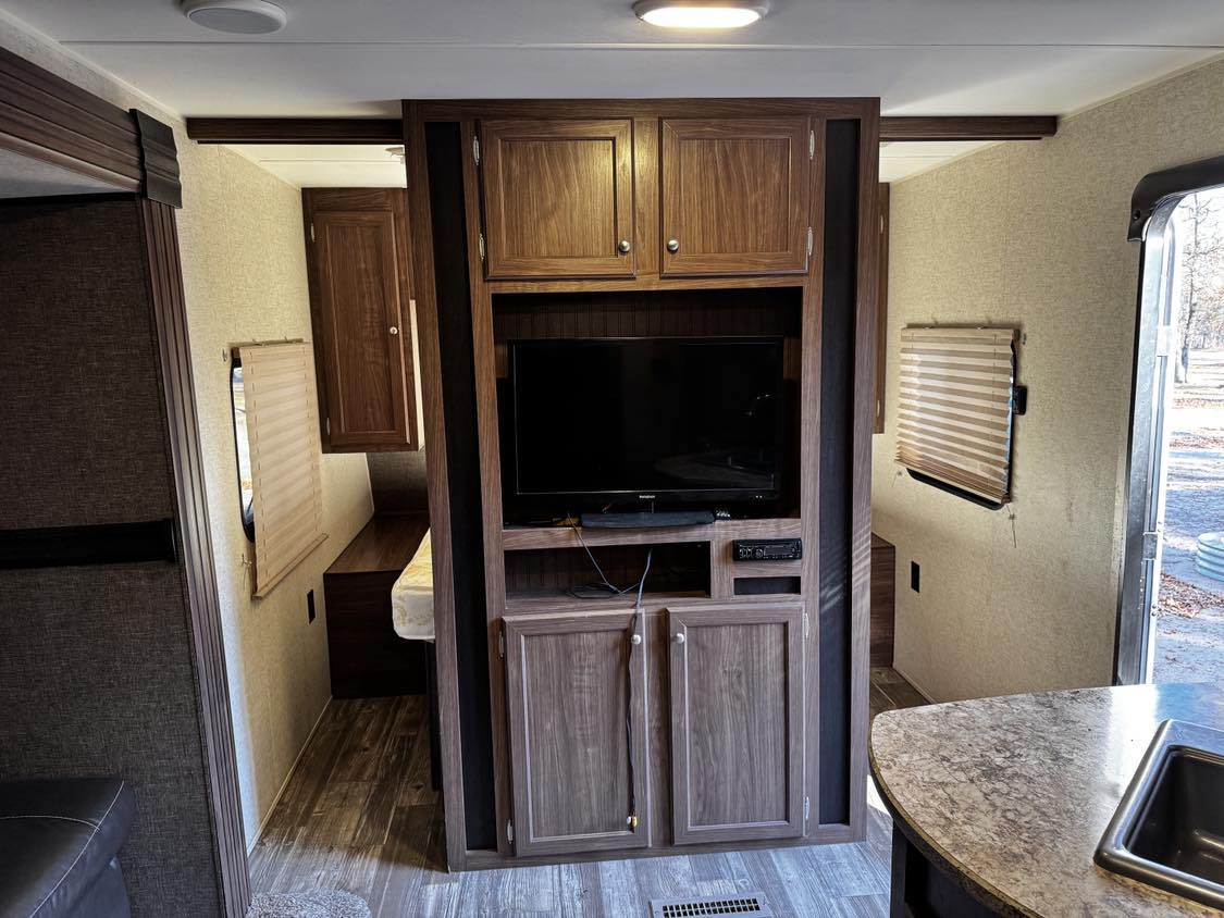 Inside this RV rental: a compact living space with entertainment center, sleeping areas, and kitchen counter with sink.. Heartland Pioneer 2016