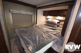 This RV rental's bedroom features a new, plastic-covered bed and pillows, efficiently recessed into the wall for compact living.. Forest River Forester 2018
