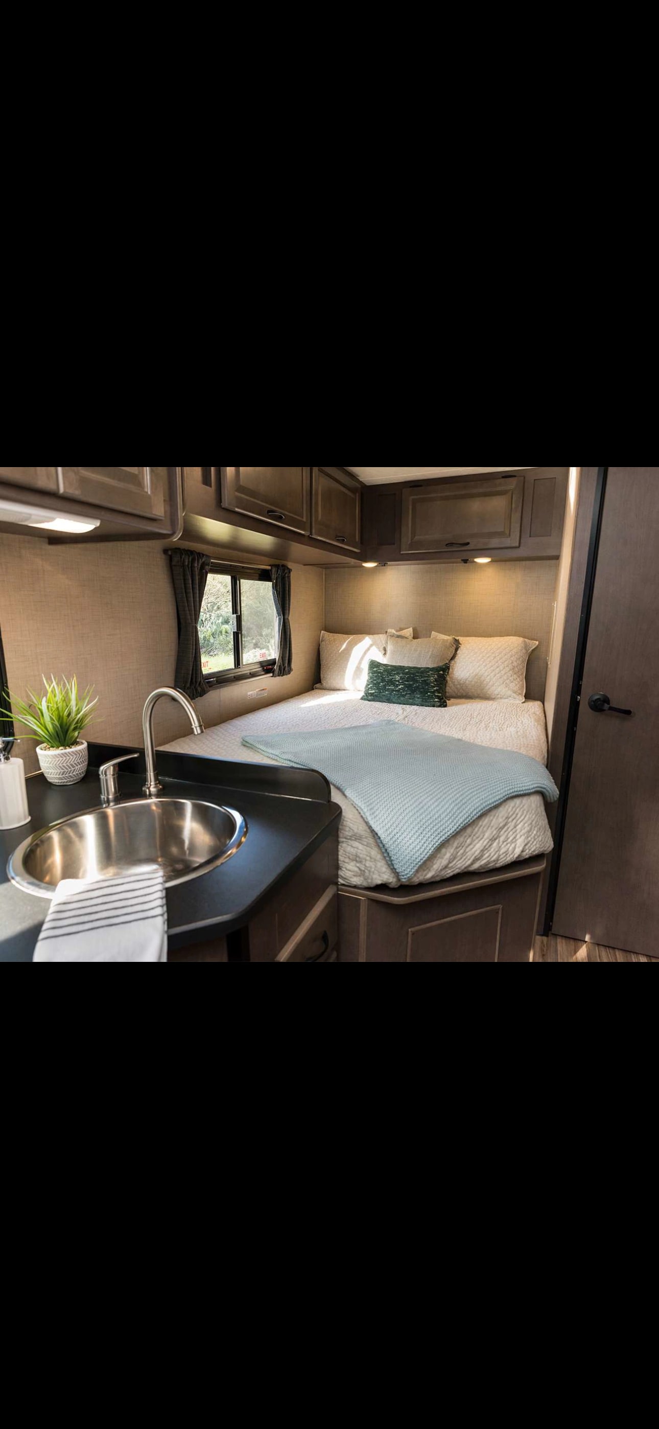 Cozy RV rental interior featuring a bed, sink, and cabinets, offering comfort for compact living.. Thor Majestic 2021