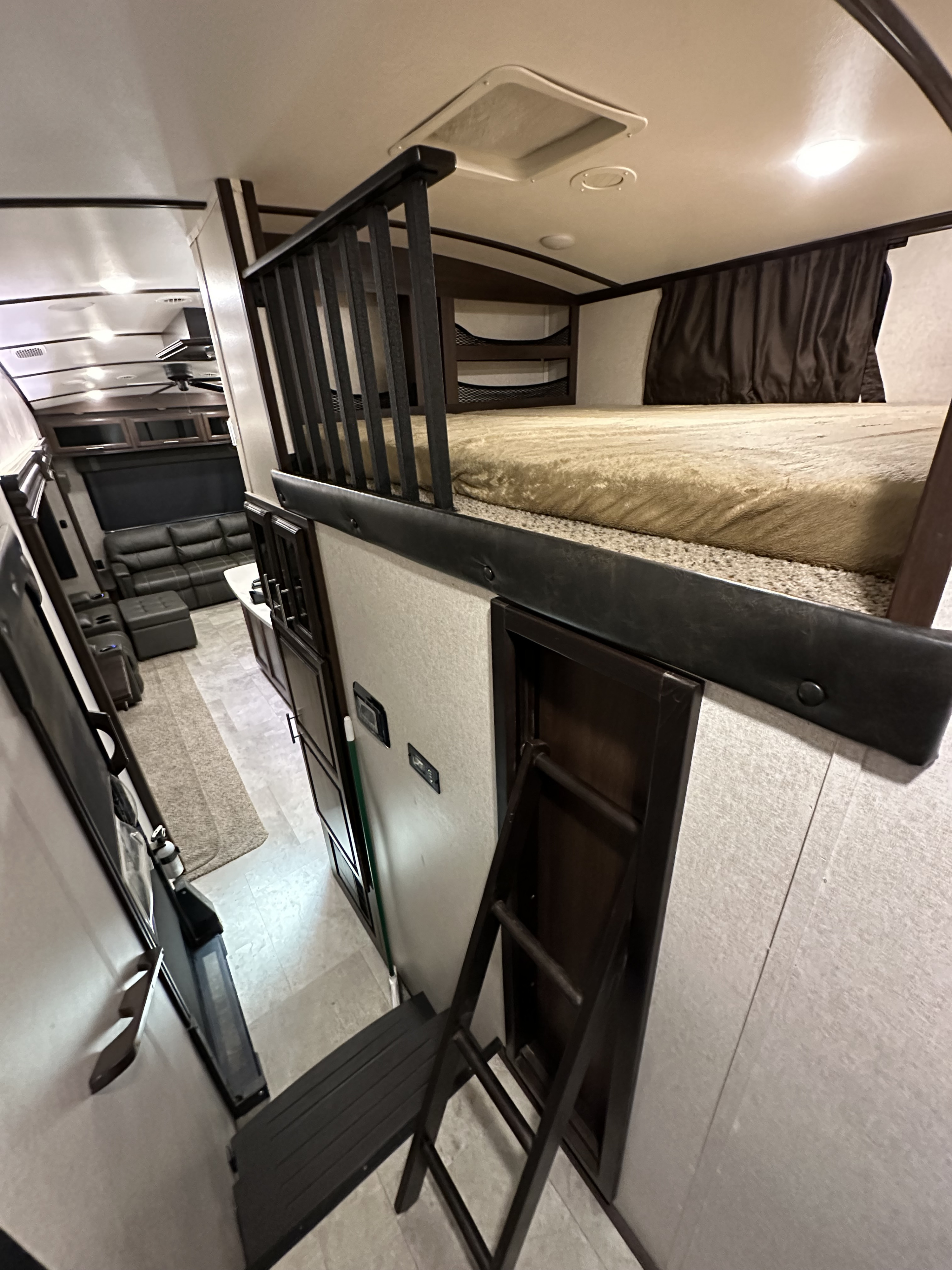 Spacious RV rental interior featuring a cozy loft bed, comfortable living area with a sofa, and portable ladder.. Jayco North Point 2018