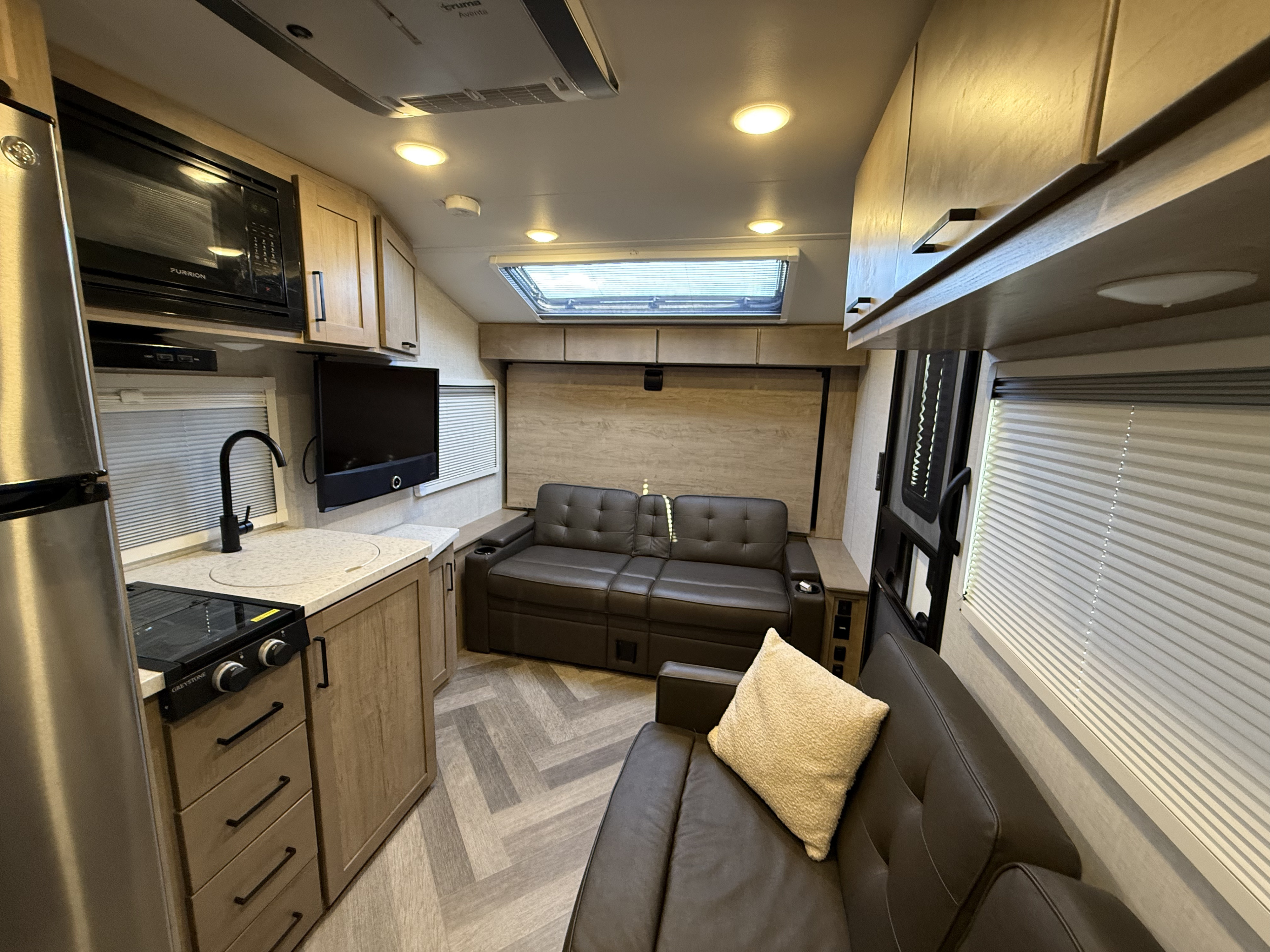 Bright camper interior with kitchen, lounge, television, and skylight