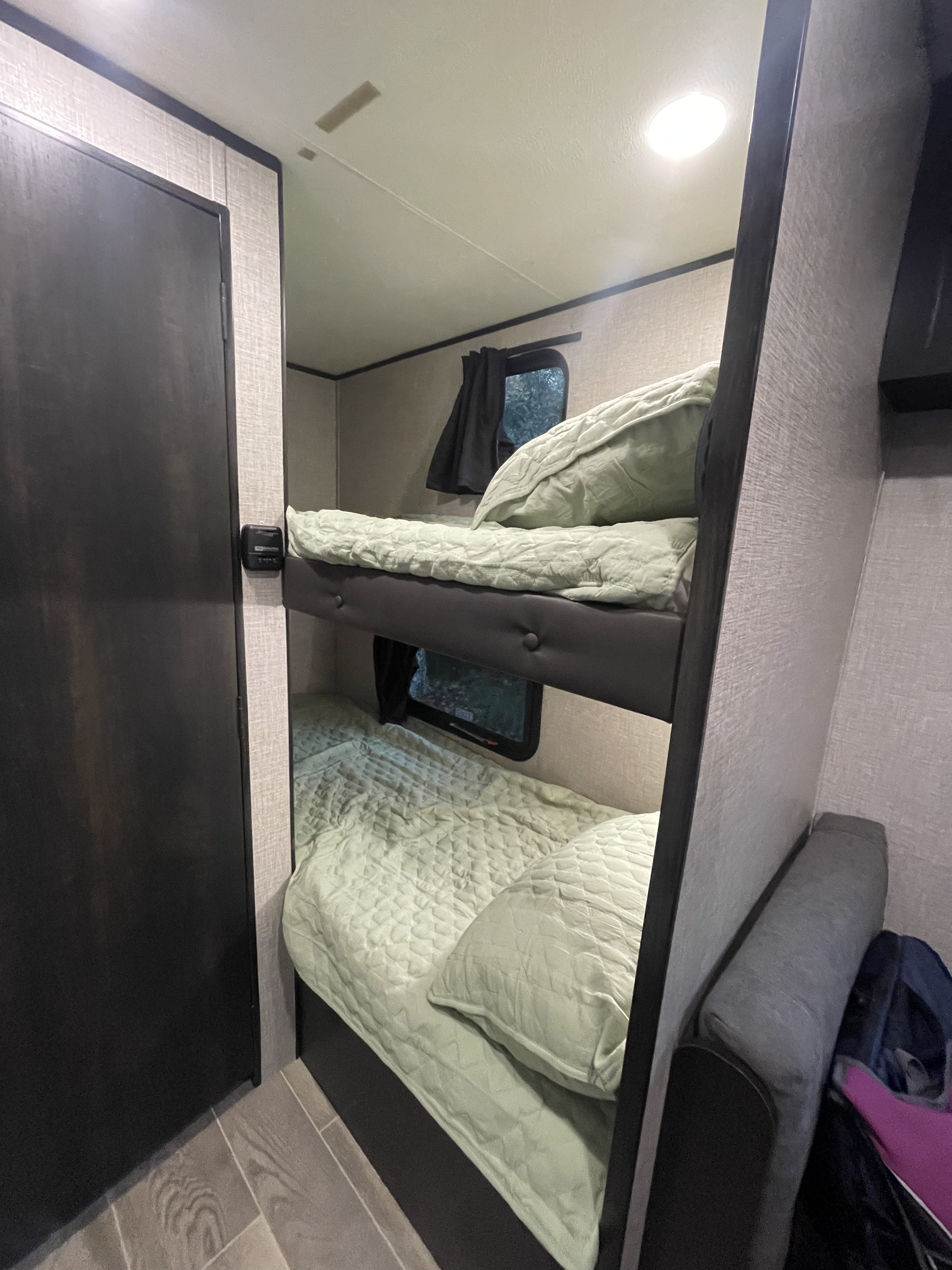 Cozy RV rental bunk beds with light green quilts and windows, perfect for family travel and camping adventures.. Jayco Jay Flight SLX 2022